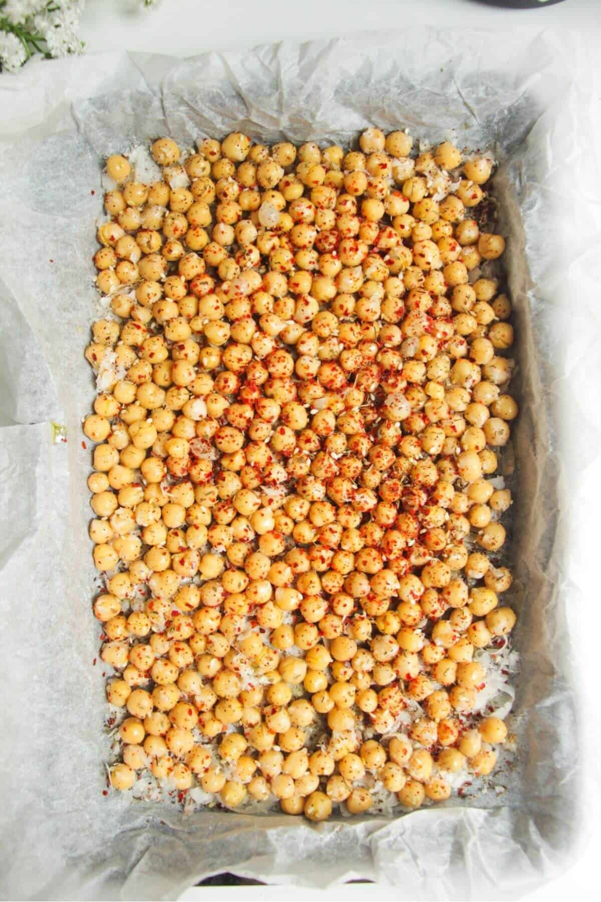 Spiced chickpeas on top of parmesan in a baking tray.