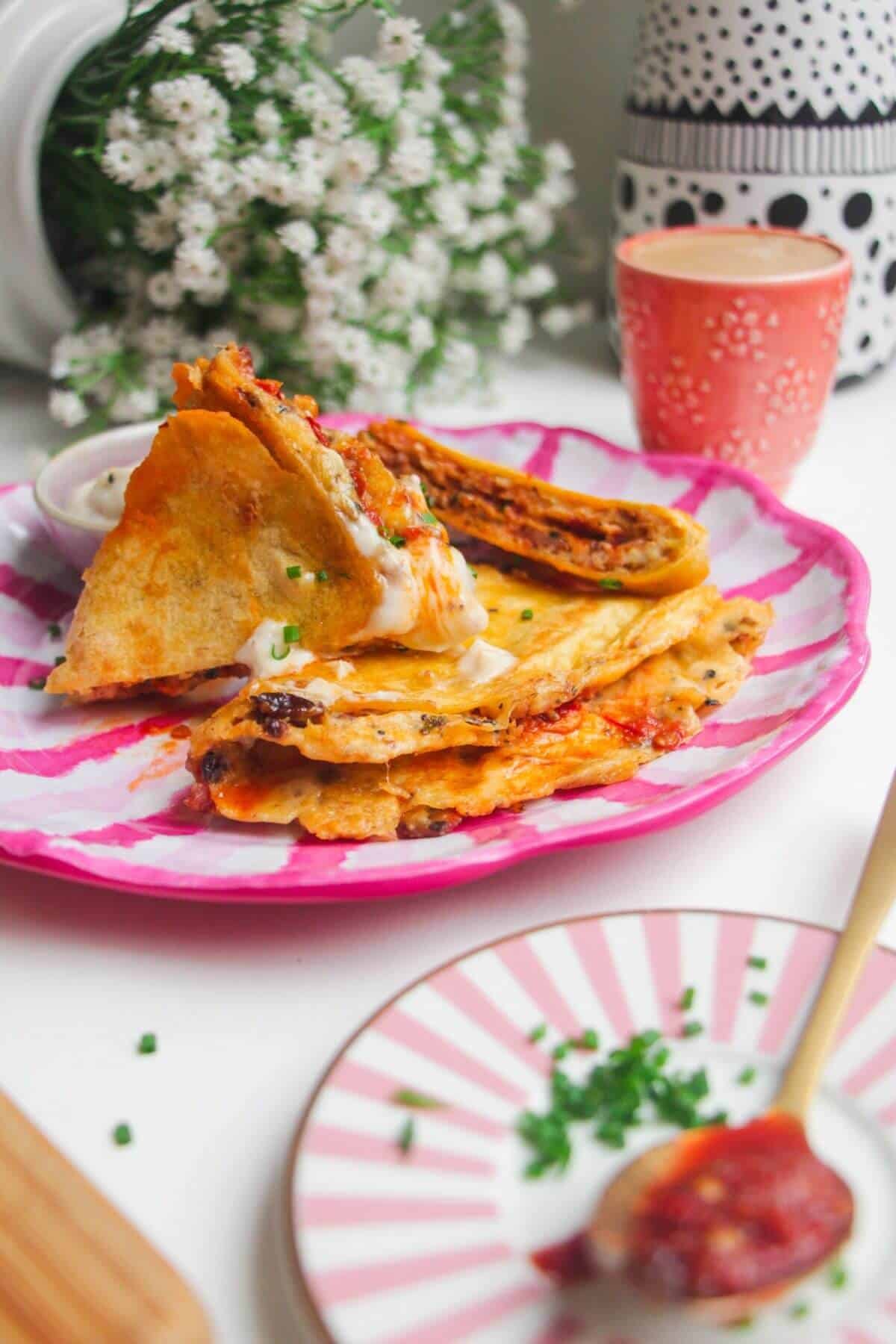 Breakfast tortilla wrap sliced on a pink and white plate.