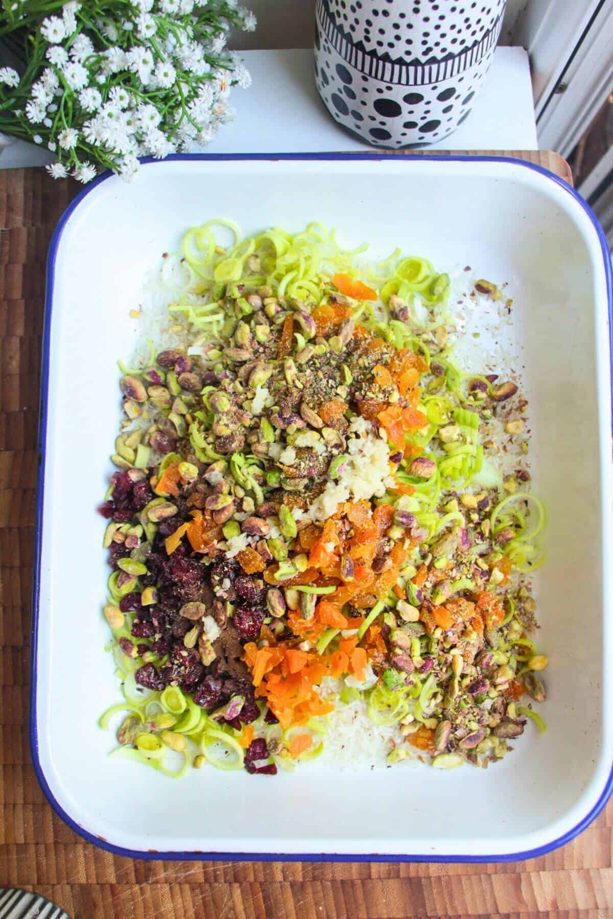 Rice, leeks and seasoning in a large white oven dish.