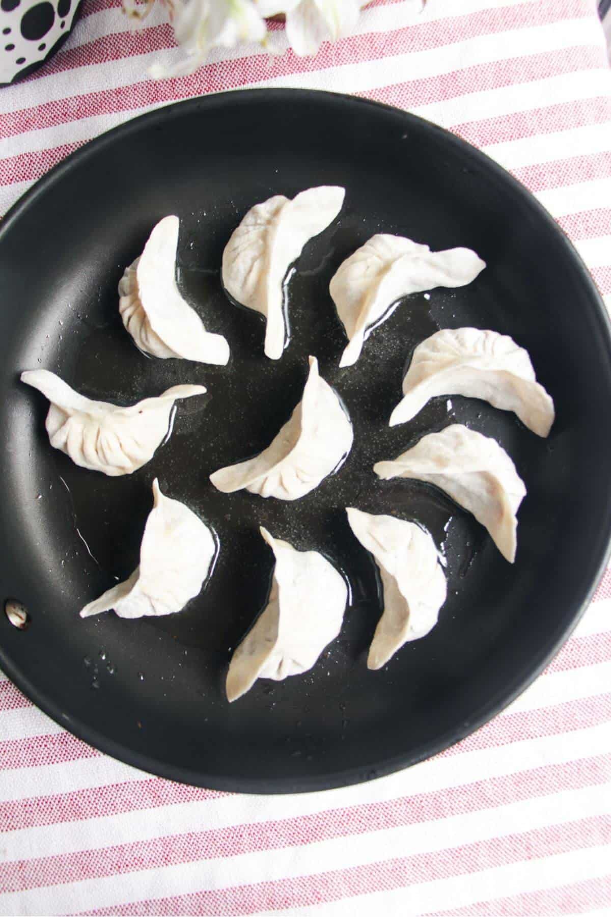 Cheeseburger dumplings arranged in a circle in a small pan.