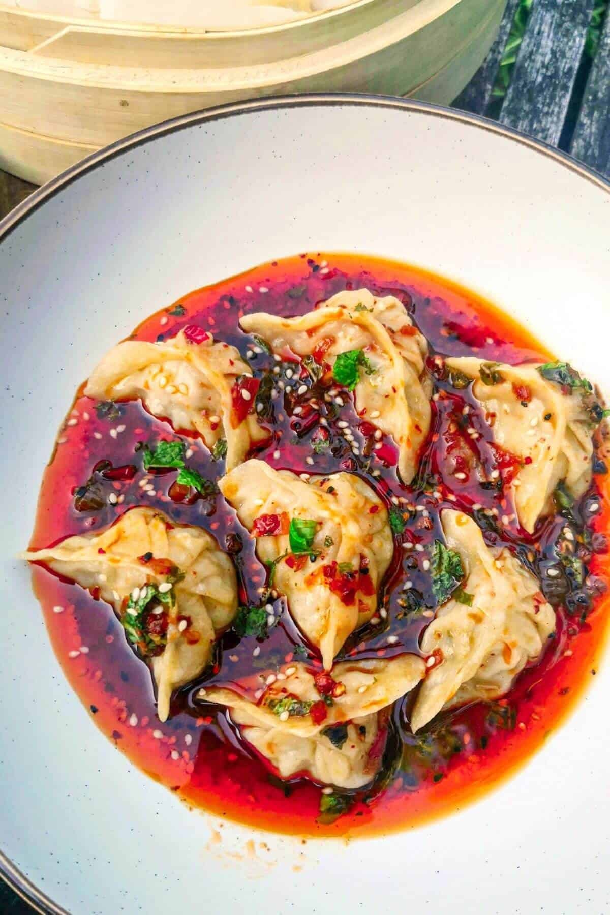 Dumplings in a bowl with red dipping sauce.