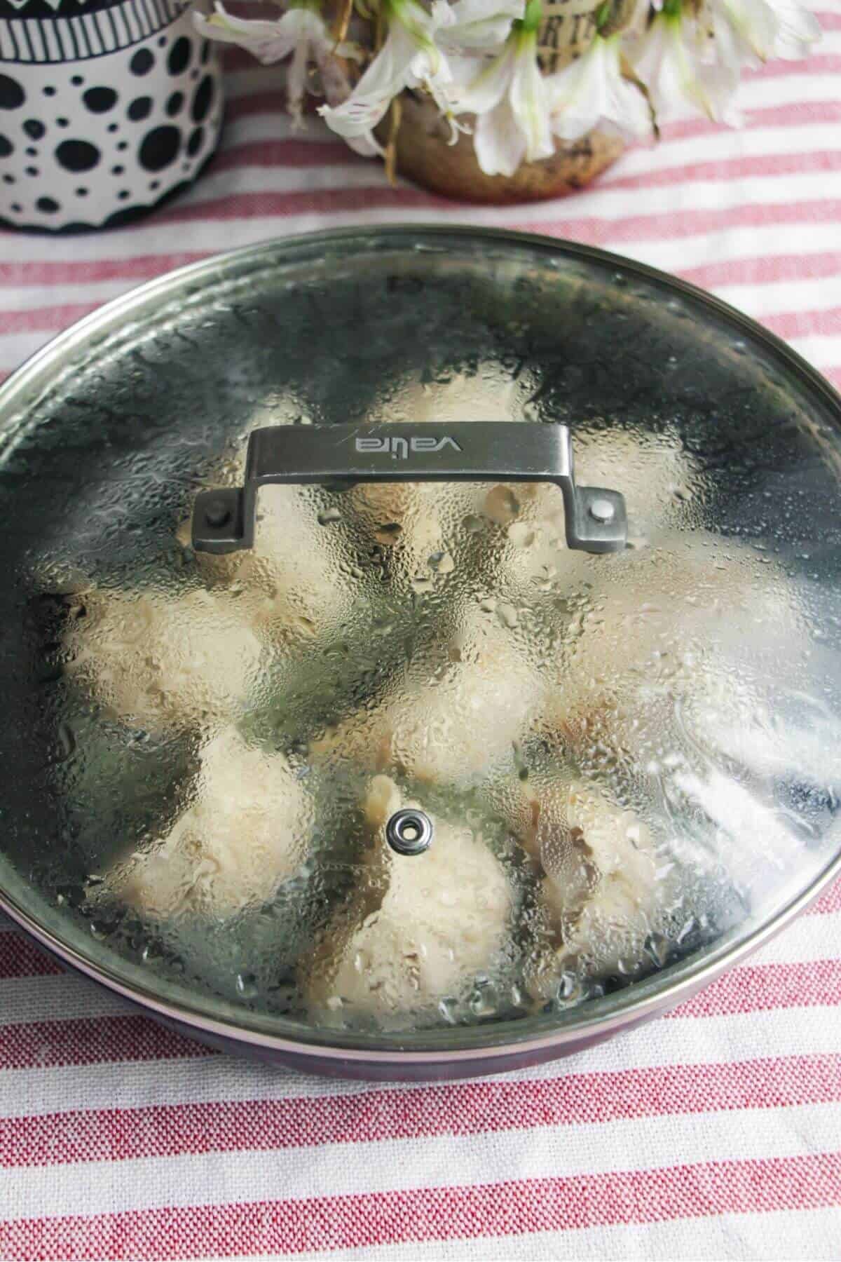 Lid on top of pan with cheeseburger dumplings inside.