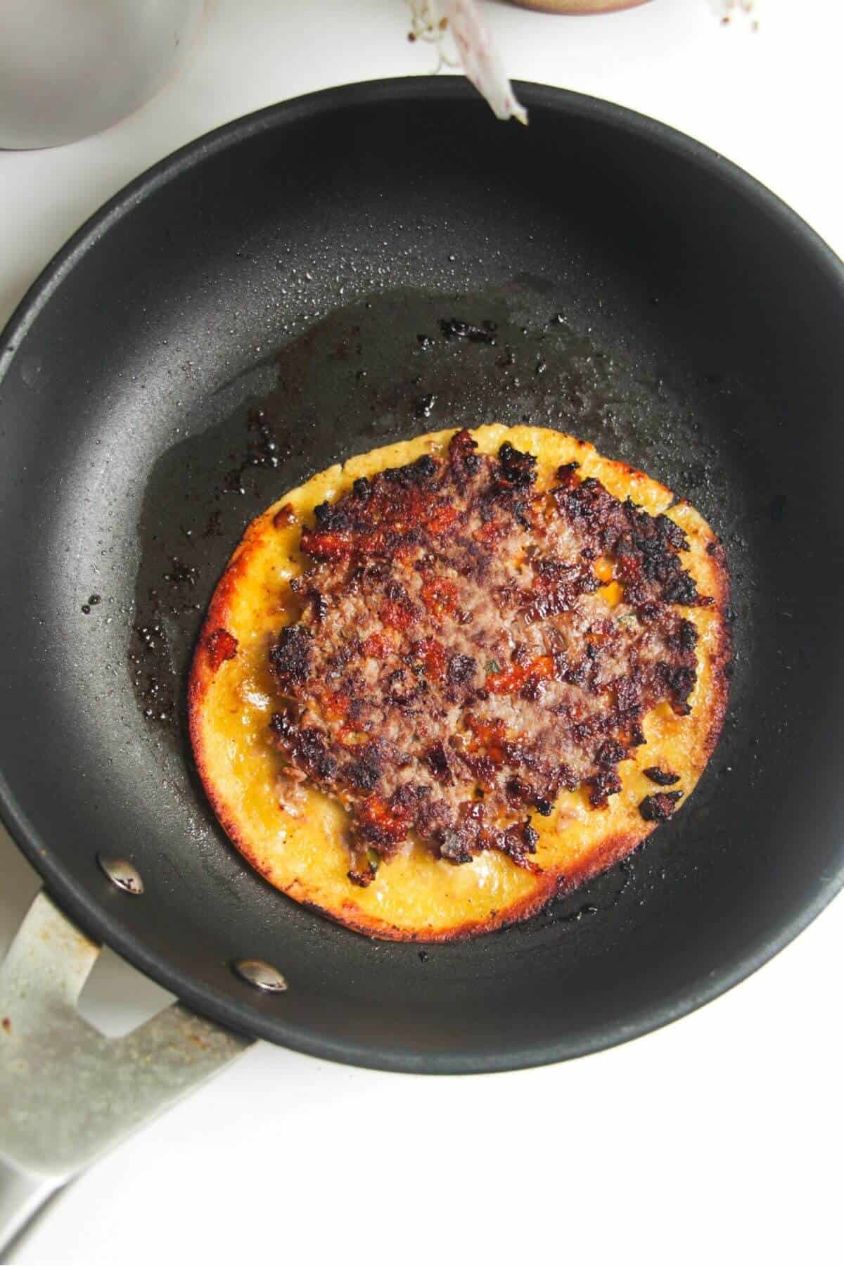 Cooked cheeseburger taco in small pan.