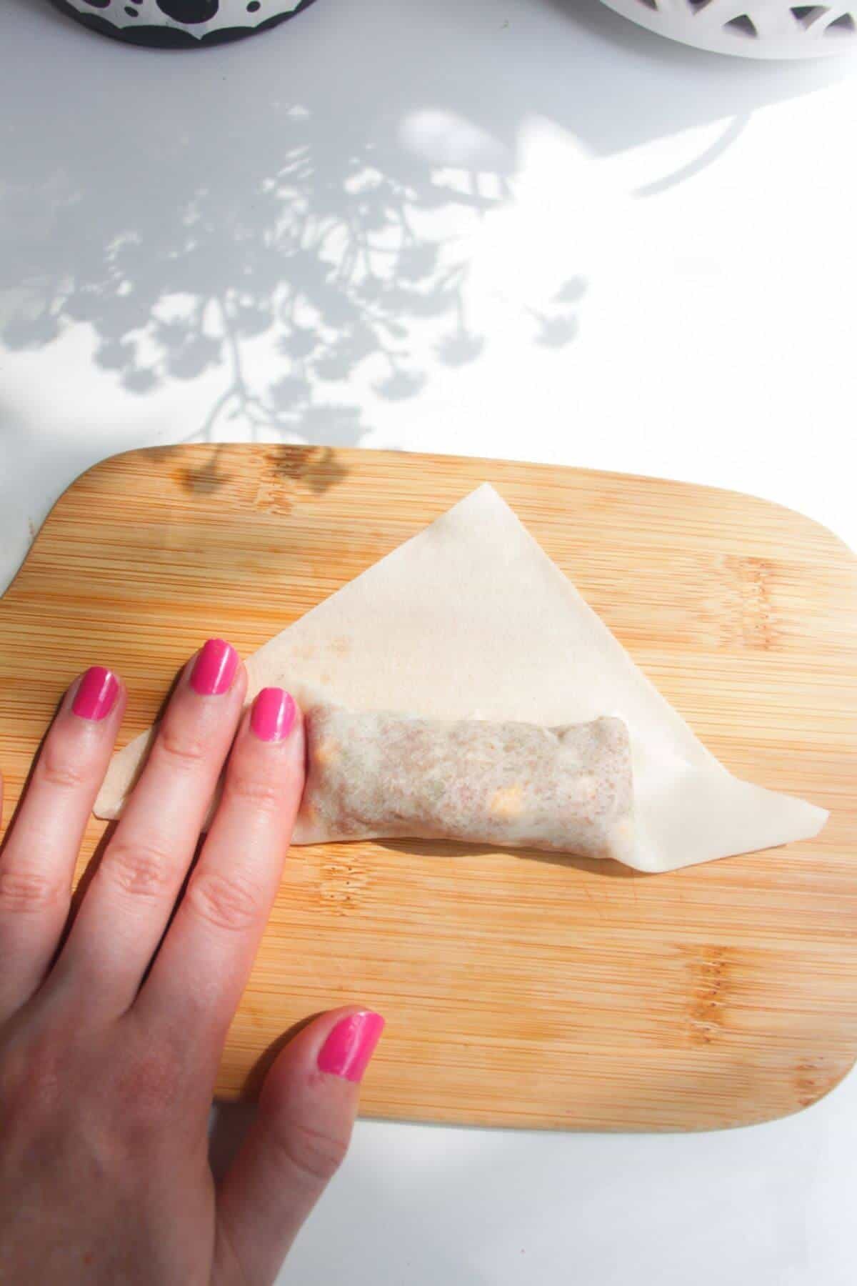 Hands folding up cheeseburger spring roll.
