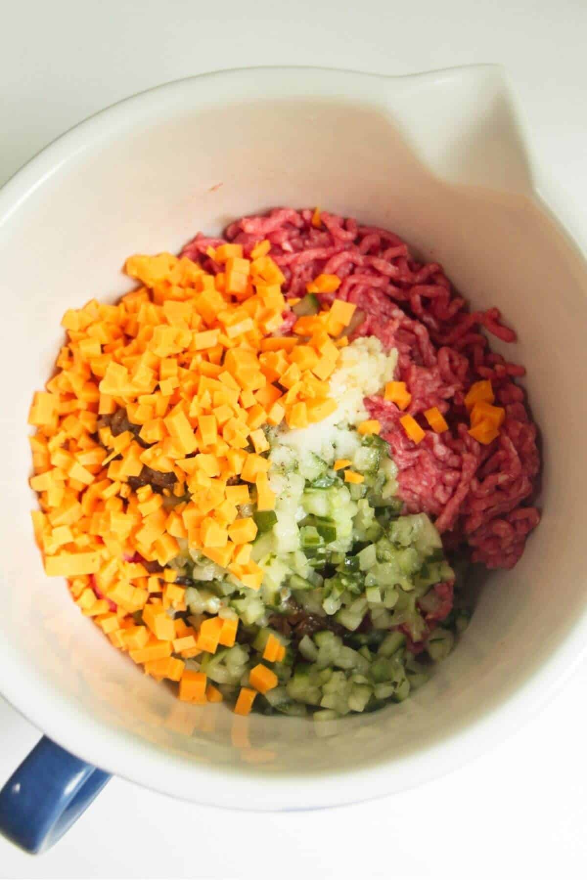 Cheese, pickles, ground beef in a mixing bowl.