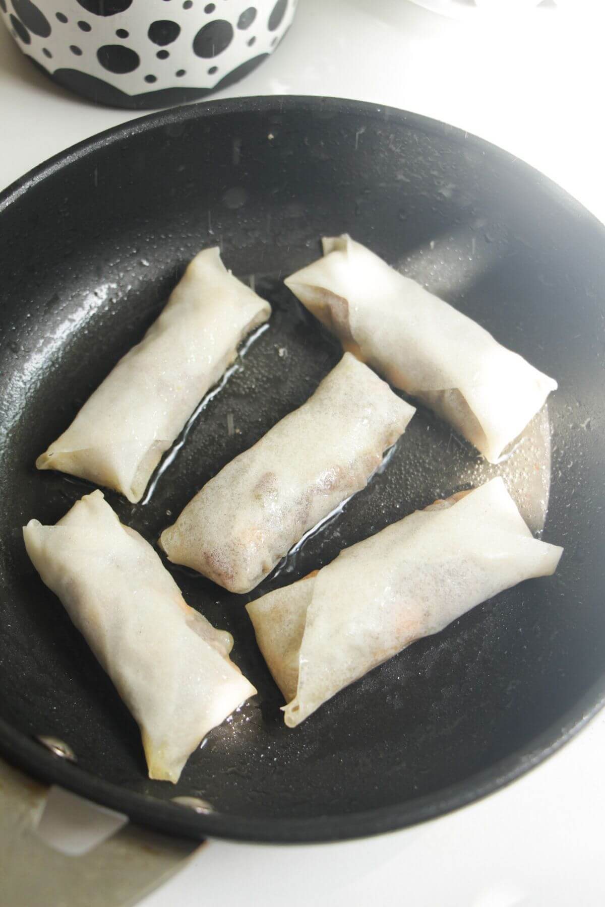 Cheeseburger spring rolls in frying pan.