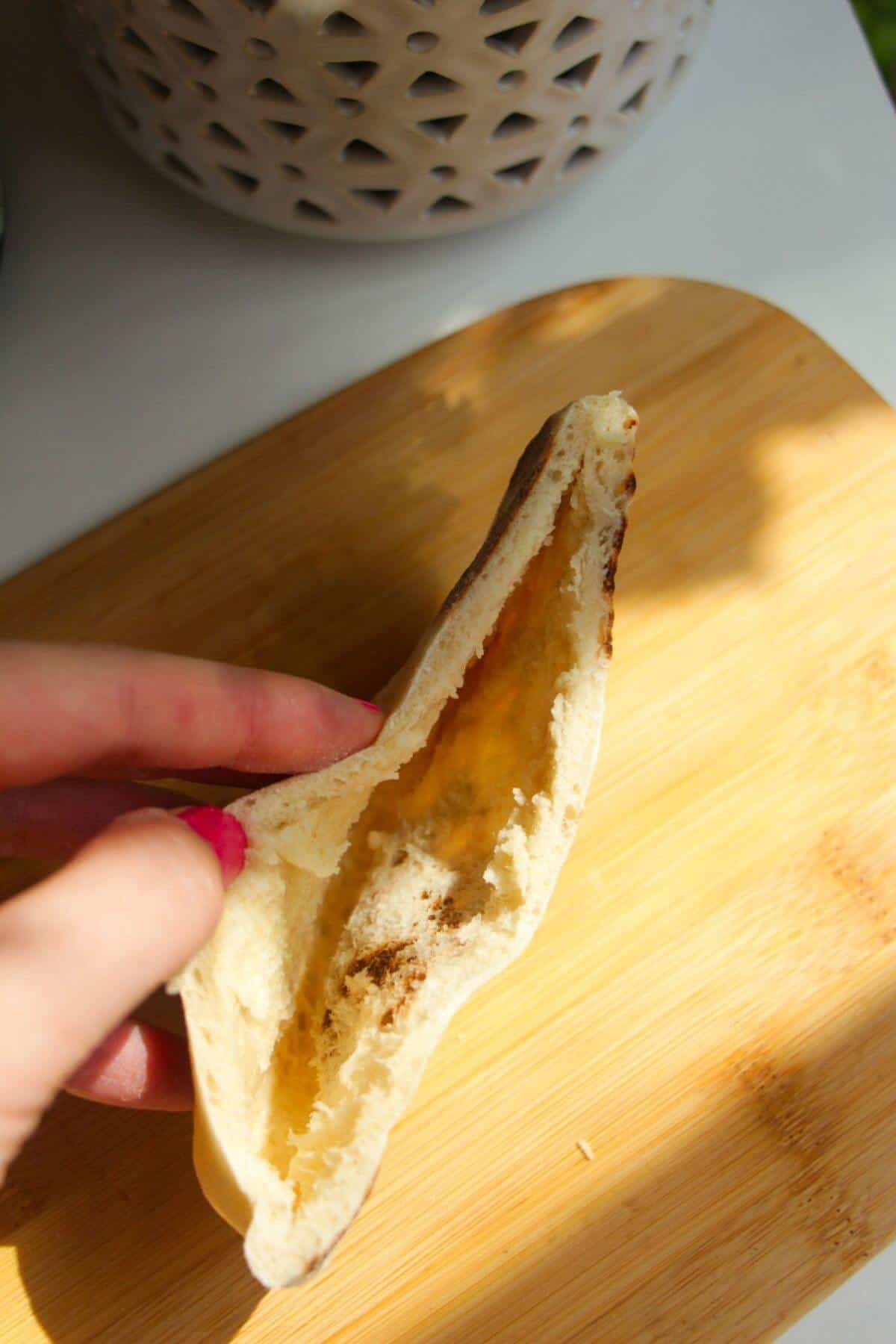 Hand holding a pita pocket open.