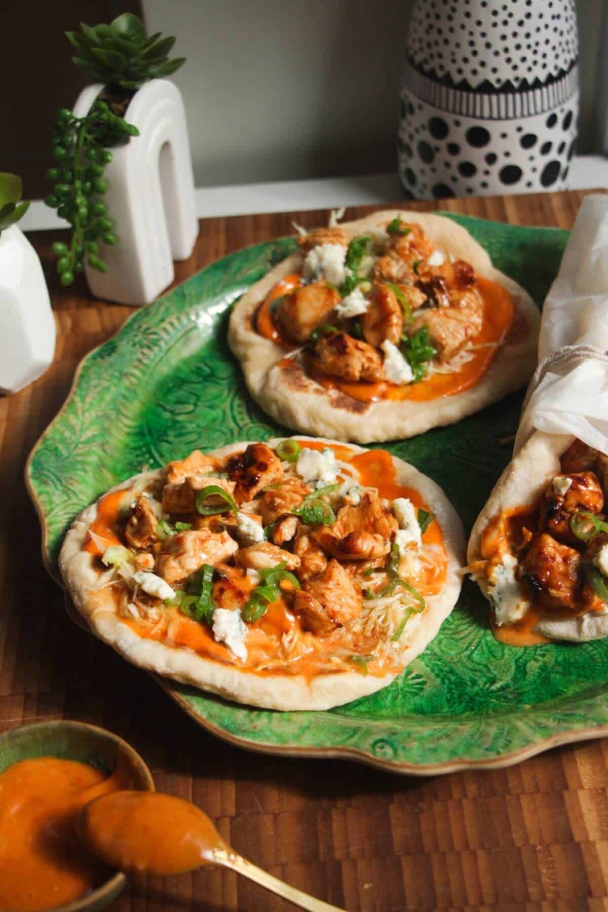 Three Buffalo chicken wraps on a large green platter.
