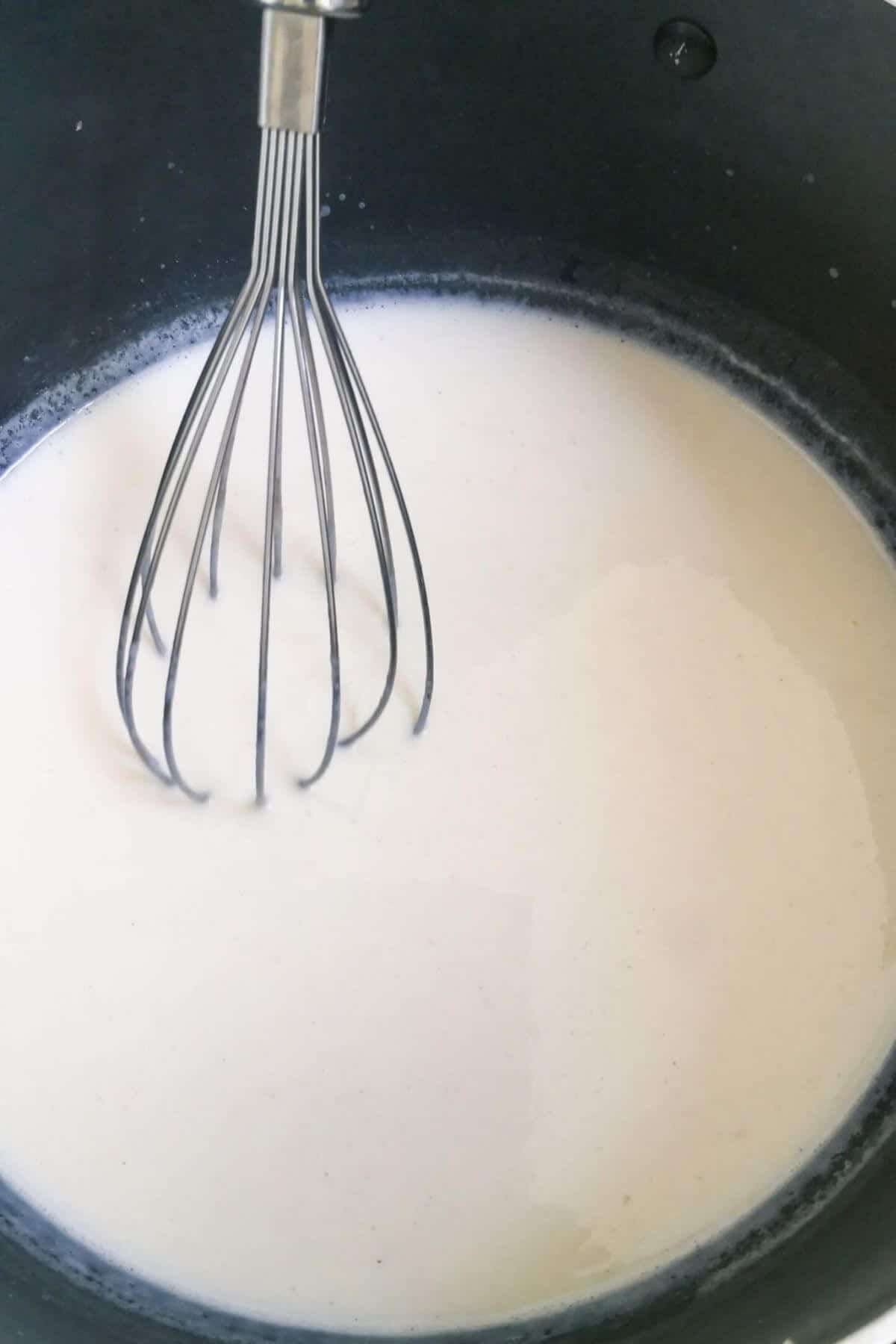 Milk being whisked in a pot.