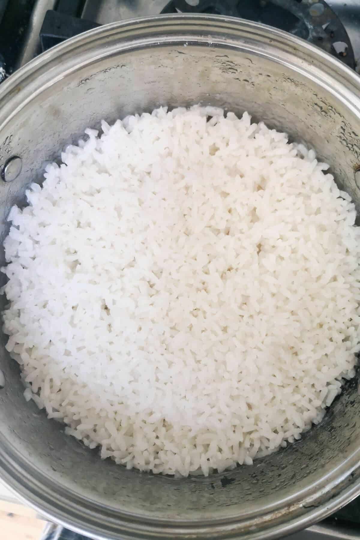 Cooked sushi rice in a small silver pot on the stove top.