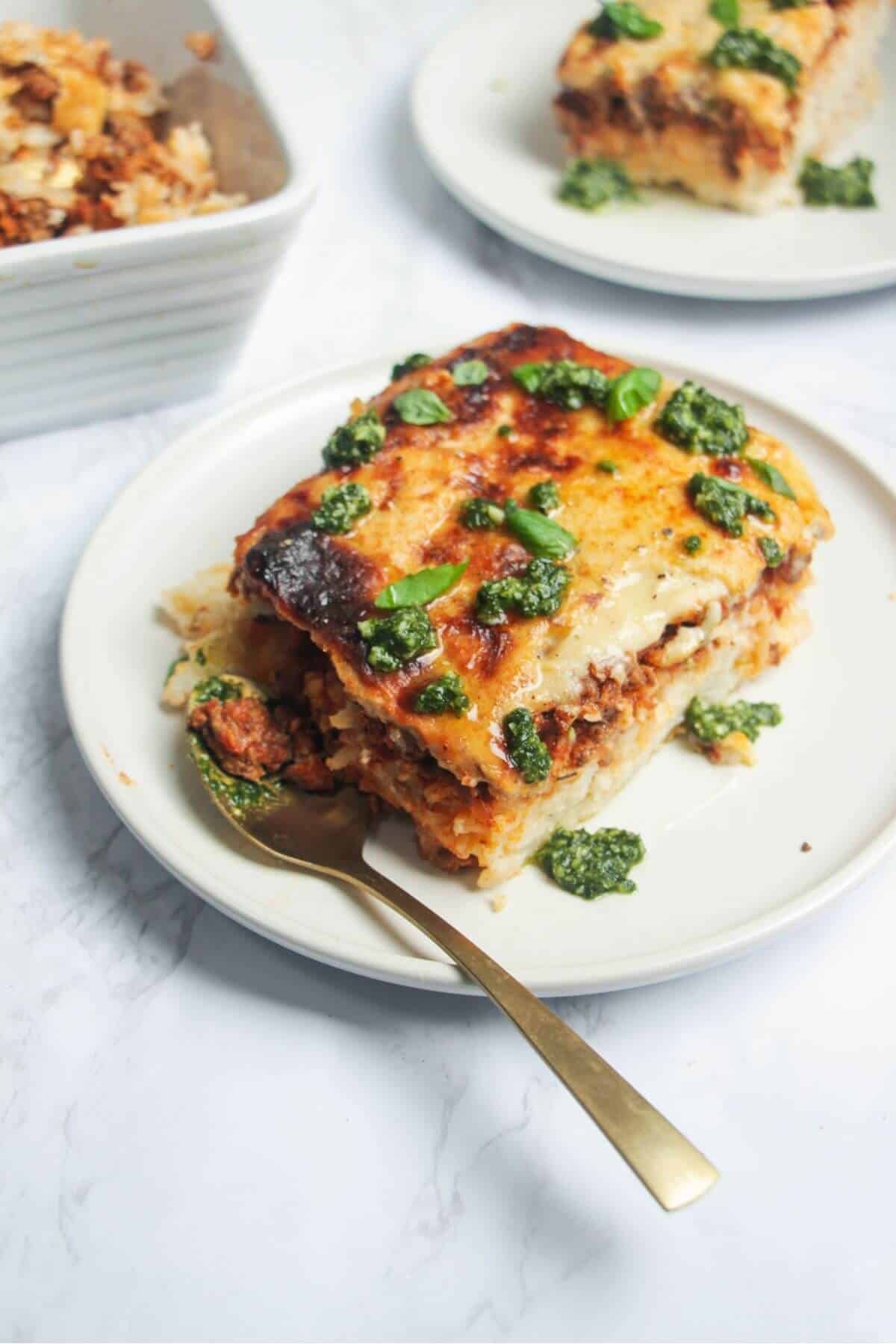 Bolognese Rice Bake on a small white plate, with another plate of the bake in the background.