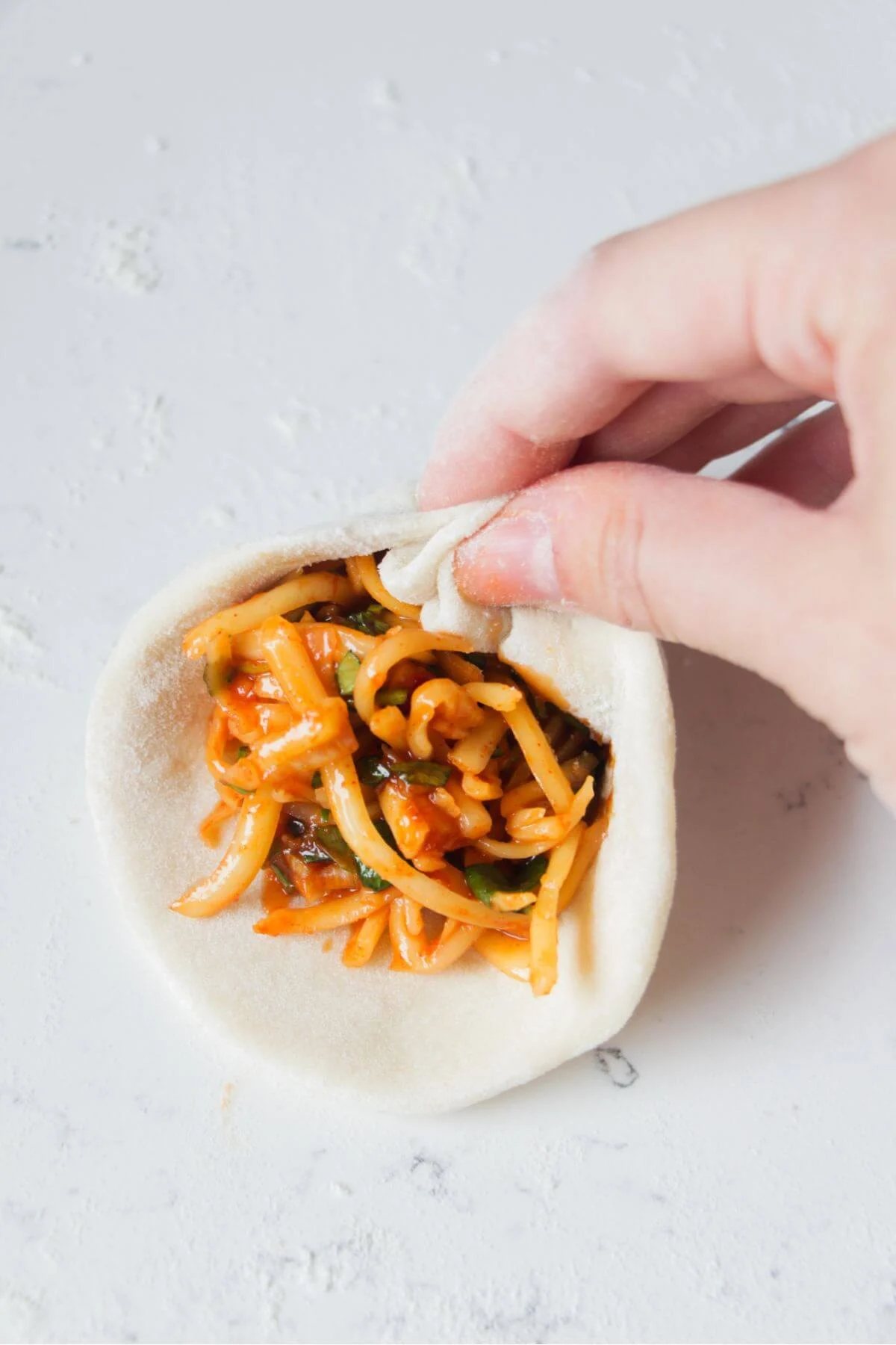 Hand folding a pizza pocket to enclose the filling.