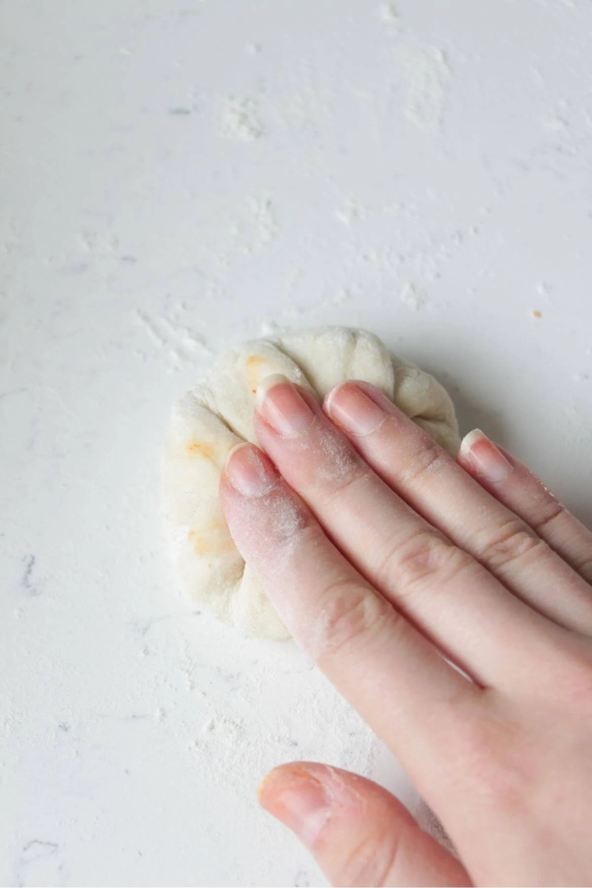 Hand pressing down on folded pizza pocket.