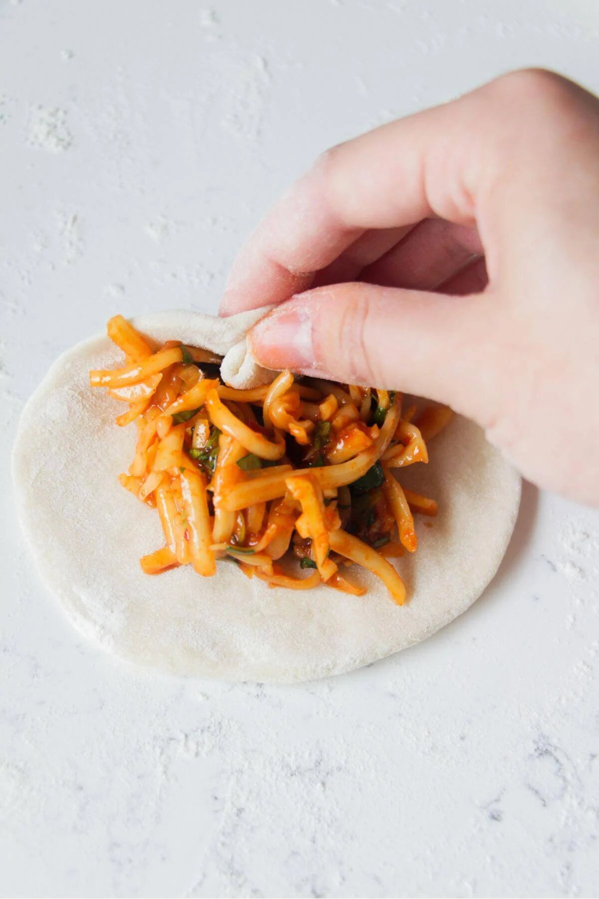 Hand folding a pizza pocket to enclose the filling.