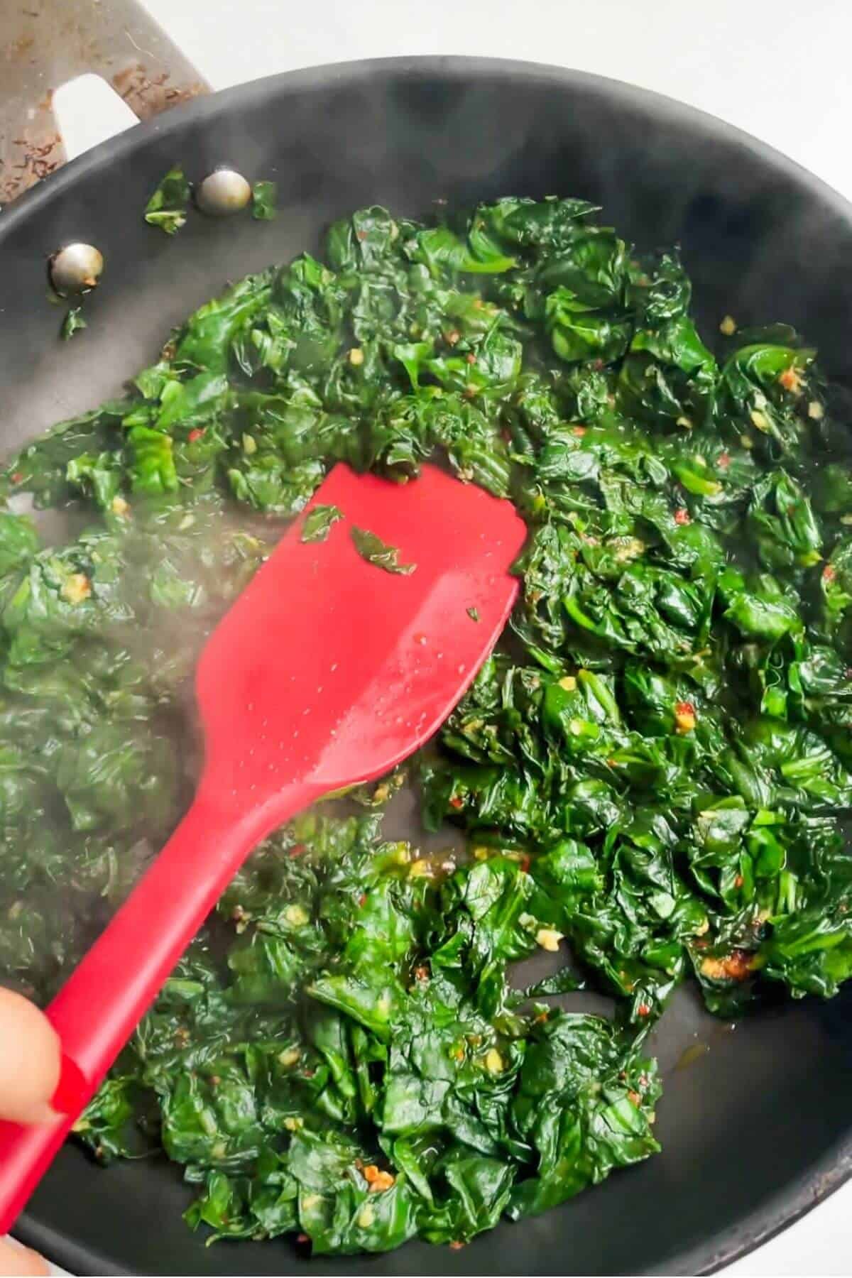Spinach wilting in a small pan.