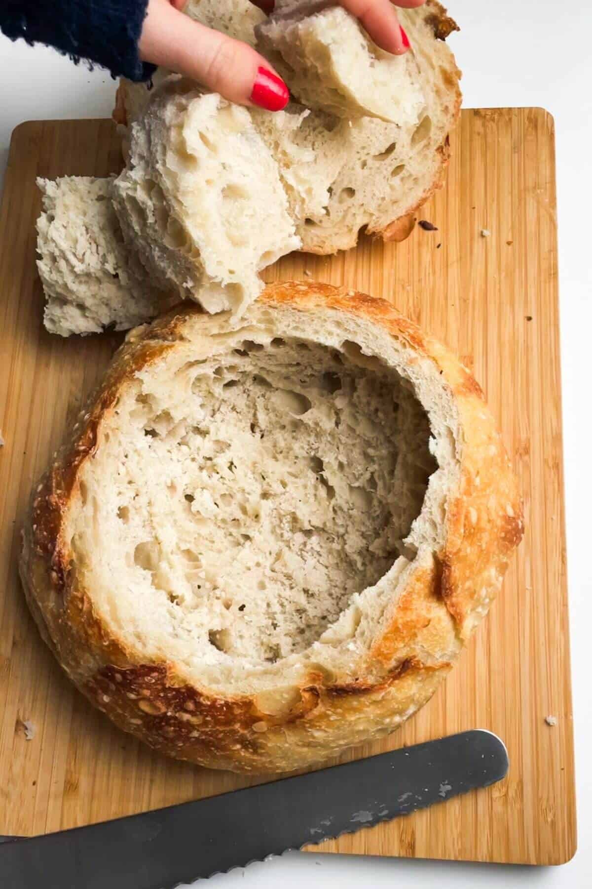 Hollowed out loaf of bread on a wooden board.