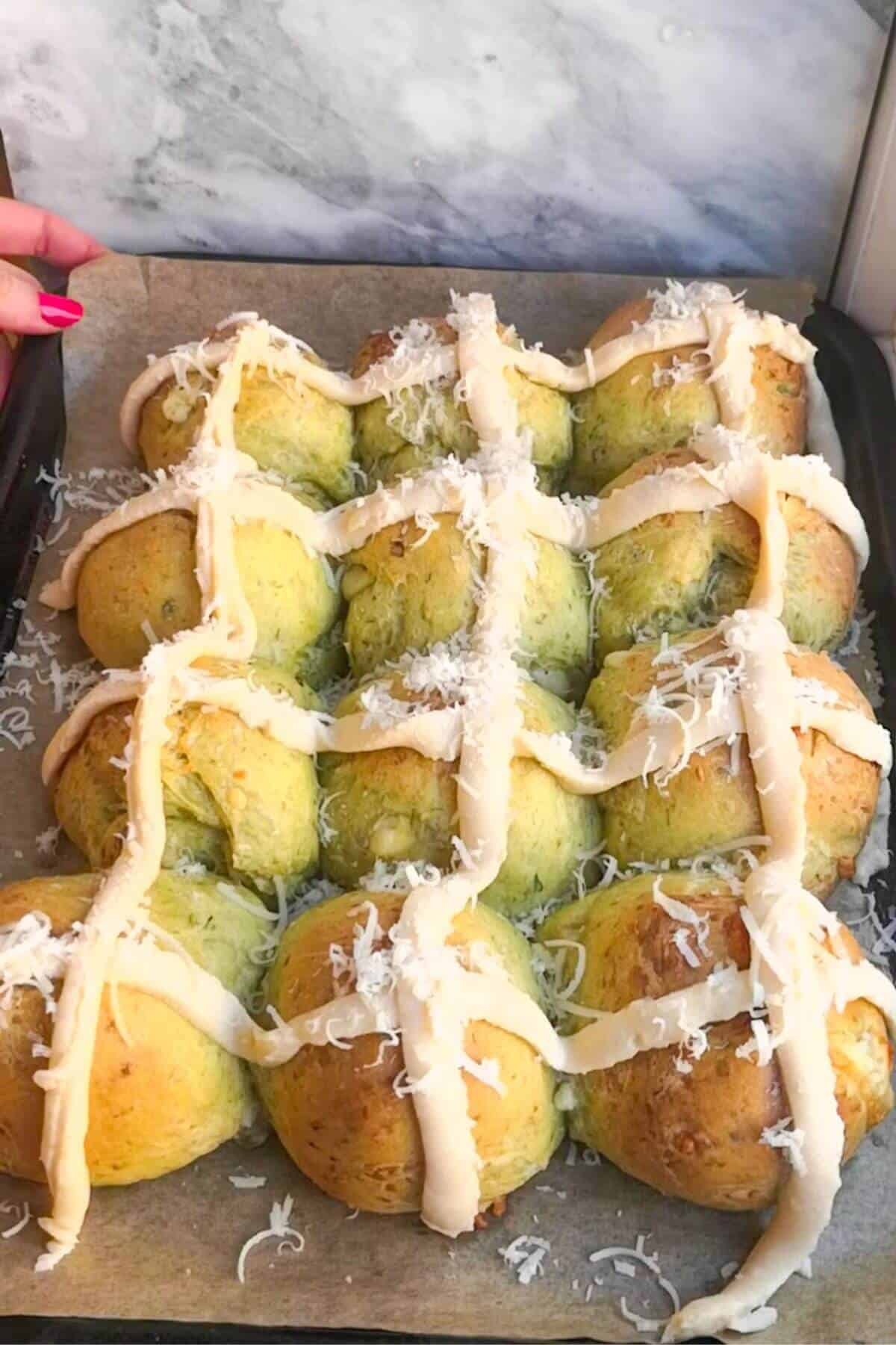 Bechamel sauce crosses on 12 wild garlic hot cross buns on an oven tray.