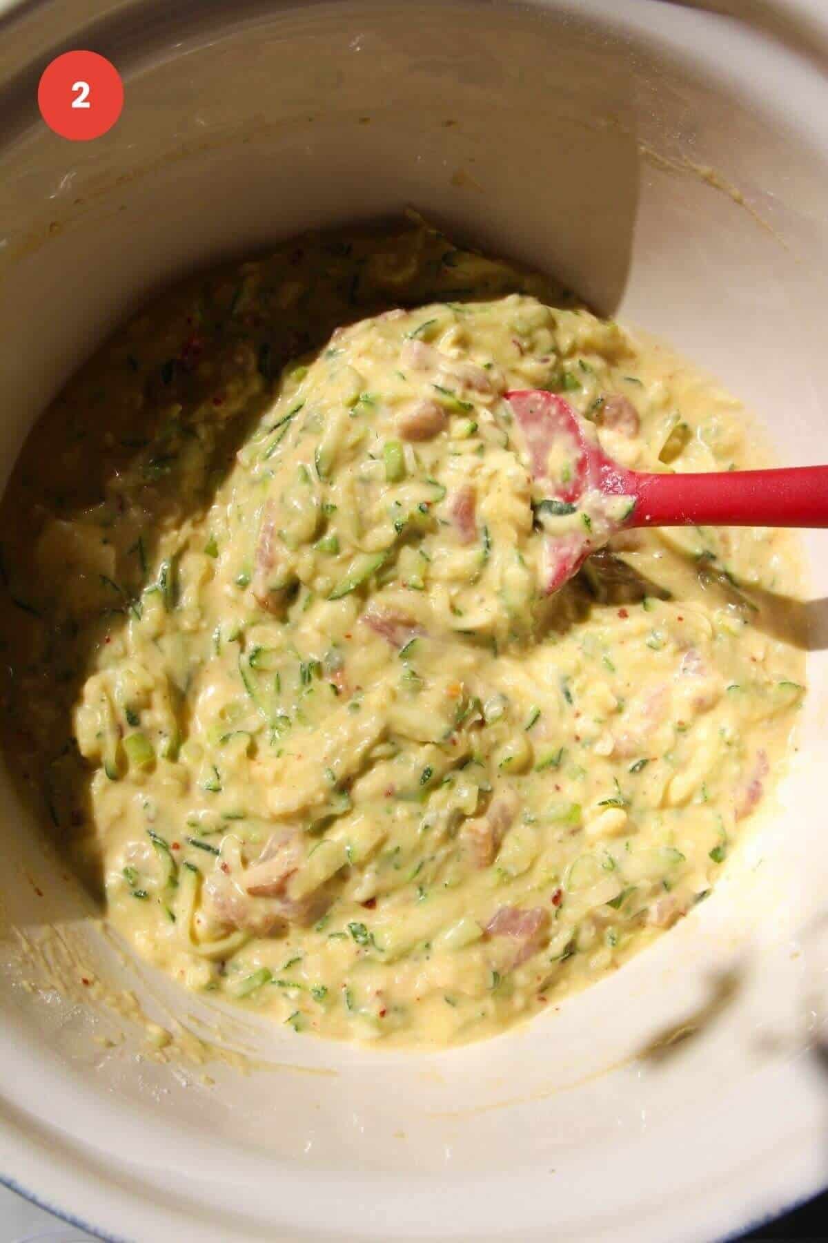 Spatula stirring ingredients for zucchini bread in bowl.