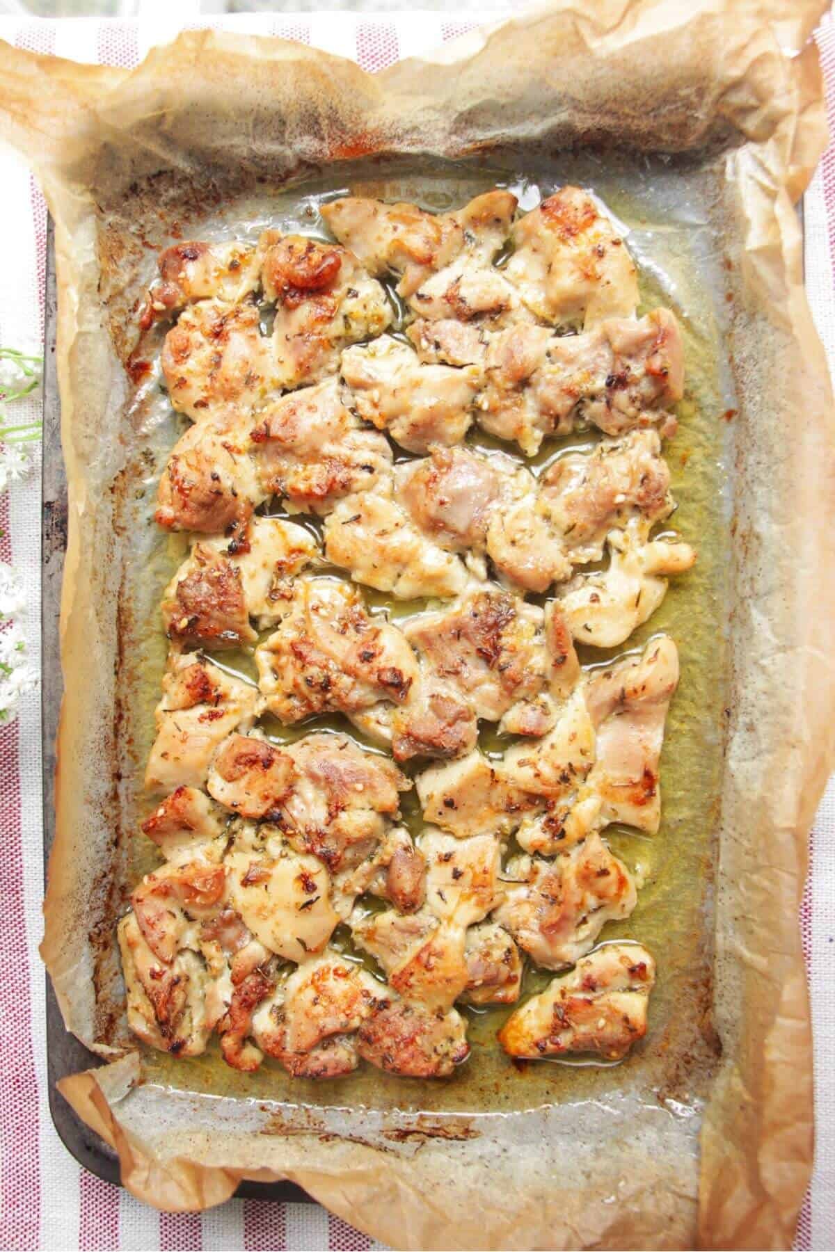 Charred cooked chicken in a lined oven tray.