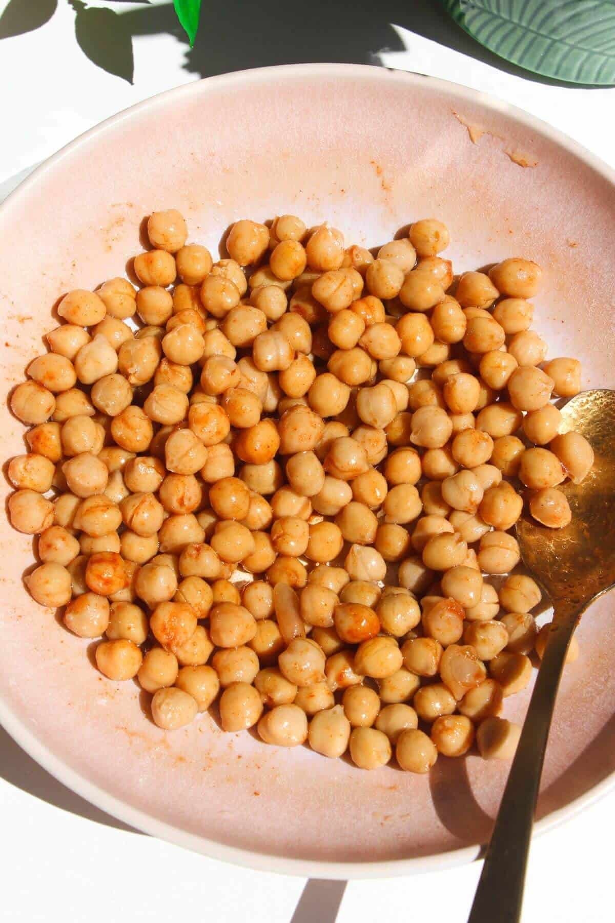 Chickpeas tossed with spices in pink bowl.