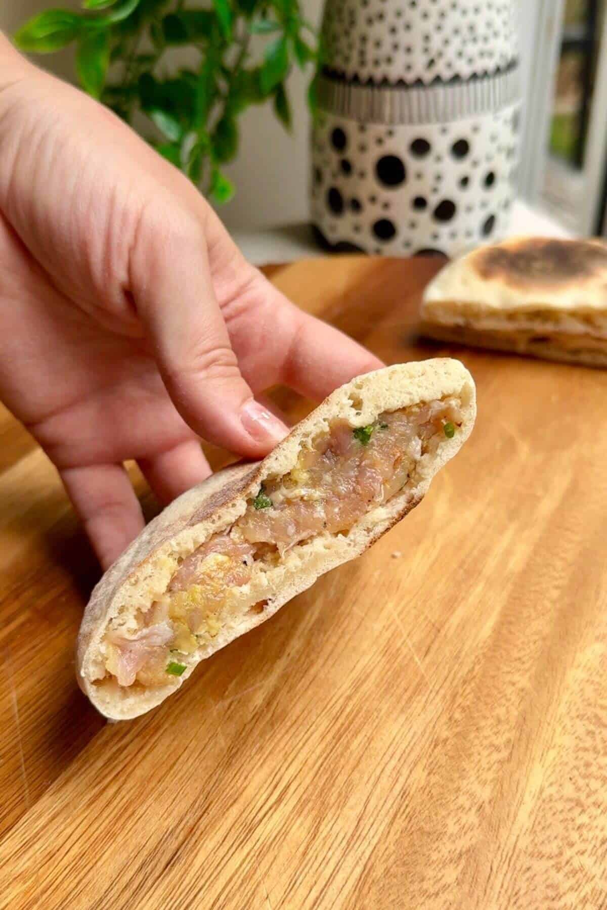 Hand holding stuffed Caesar flatbread.