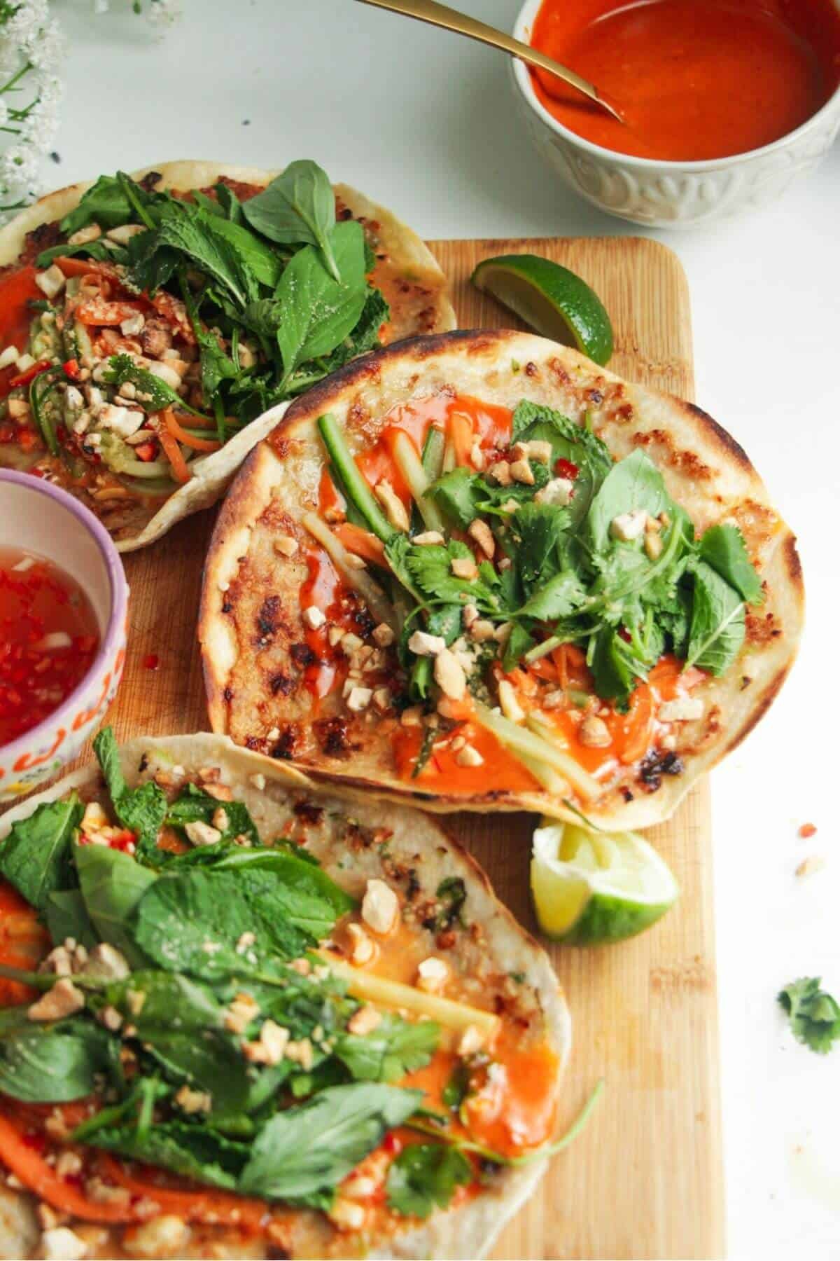 Three chicken banh mi tacos on a wooden board.