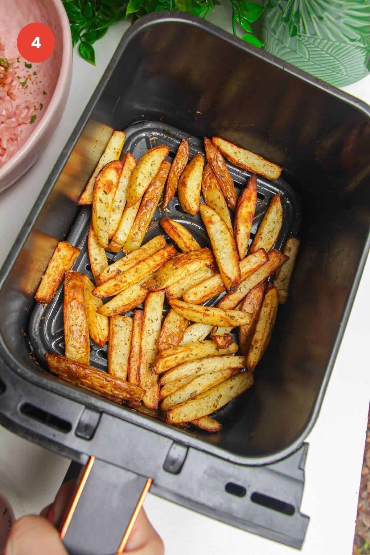 Cooked crispy fries in air fryer basket.