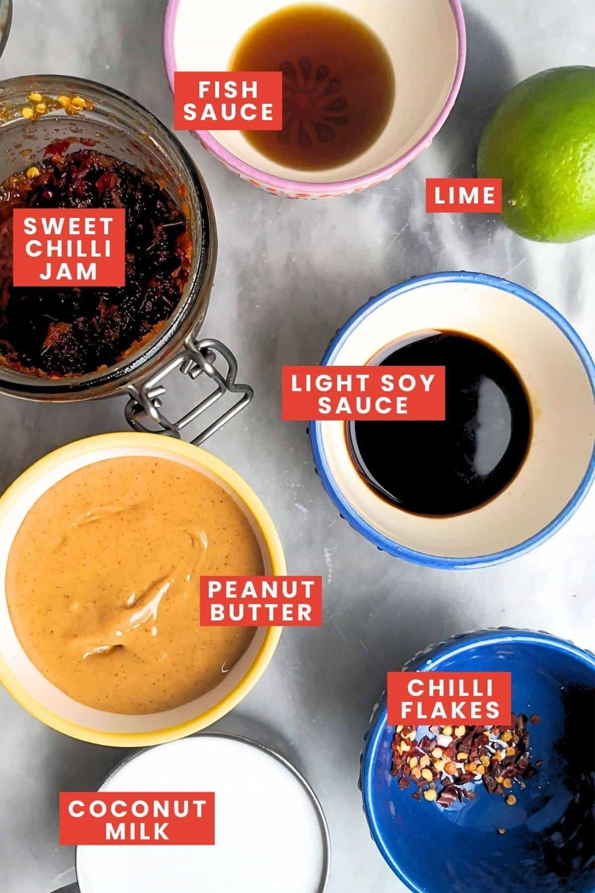 Ingredients for satay sauce, labelled and laid out on a marble bench.