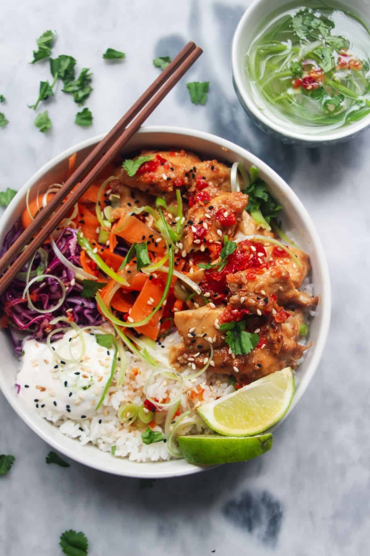 Grilled chicken poke bowl on a grey marble background.