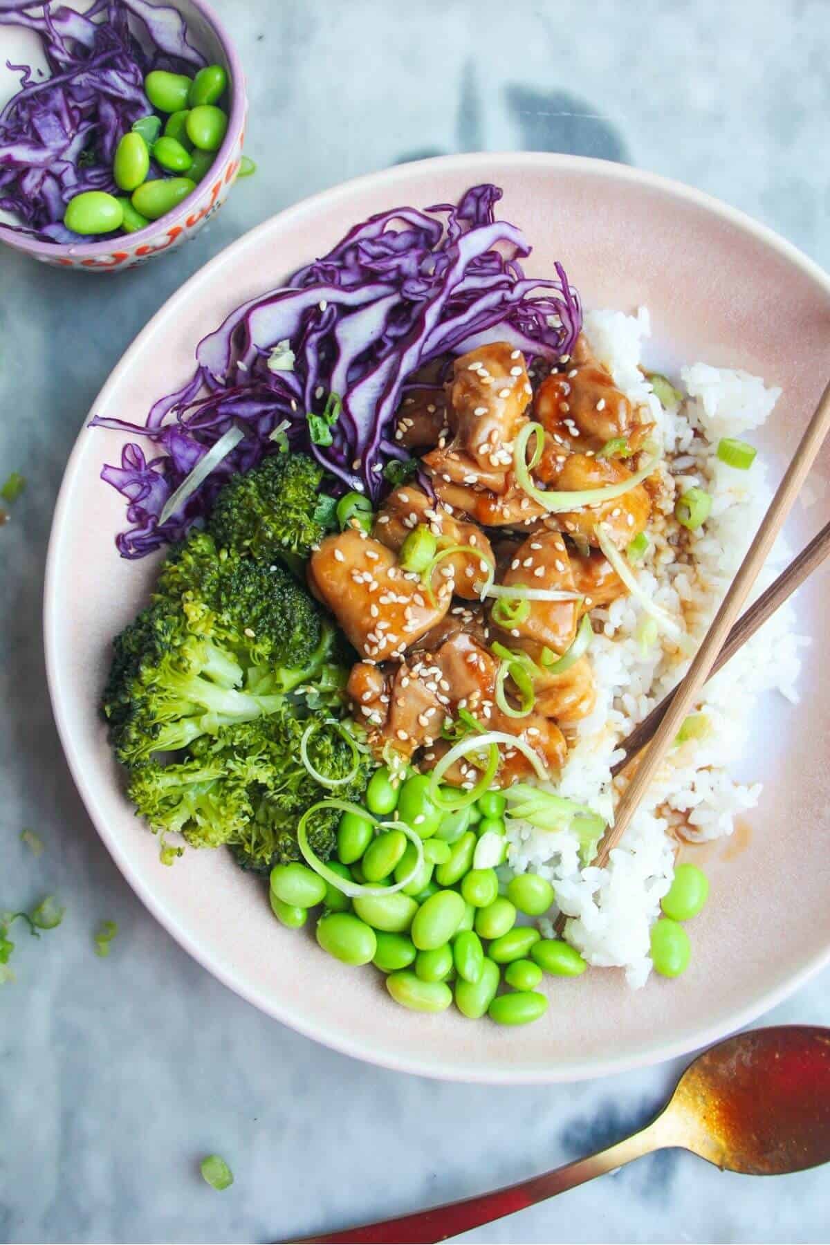 Glossy chicken teriyaki on top of rice with red cabbage, edamame and broccoli.