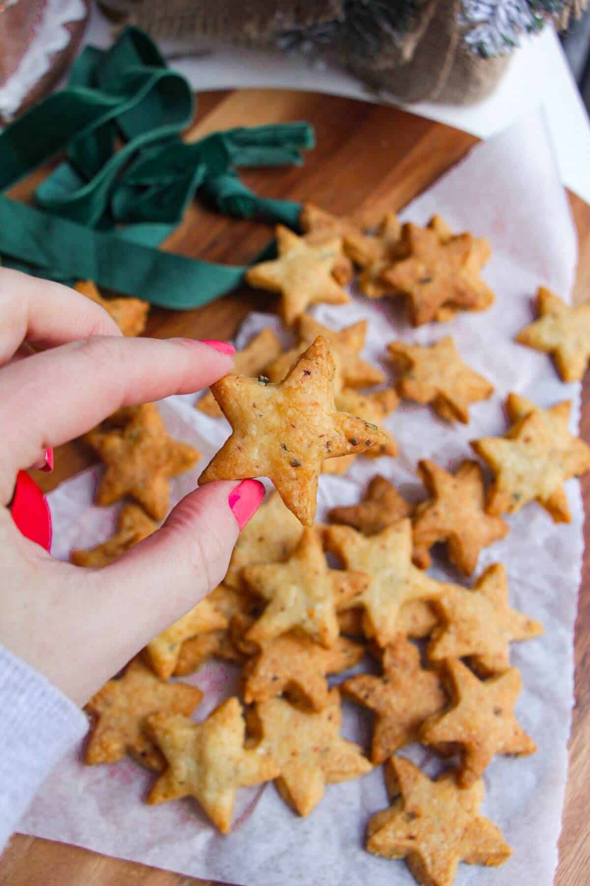 Holding a chili cheese shortbread star with more in the background.
