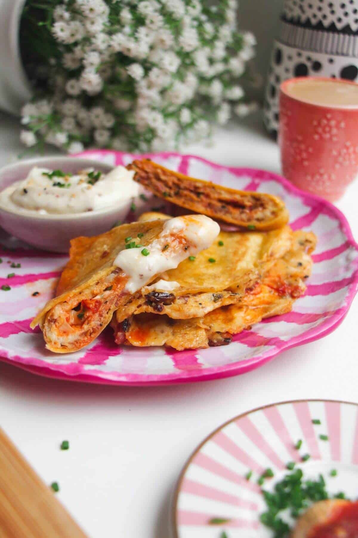 Breakfast tortilla wrap sliced on a pink and white plate.
