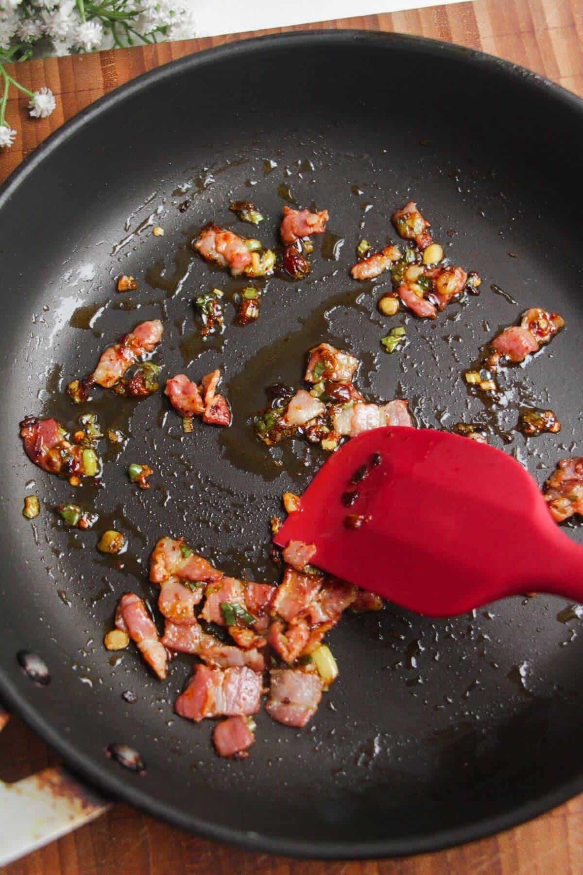 Sliced bacon and scallions in a pan.