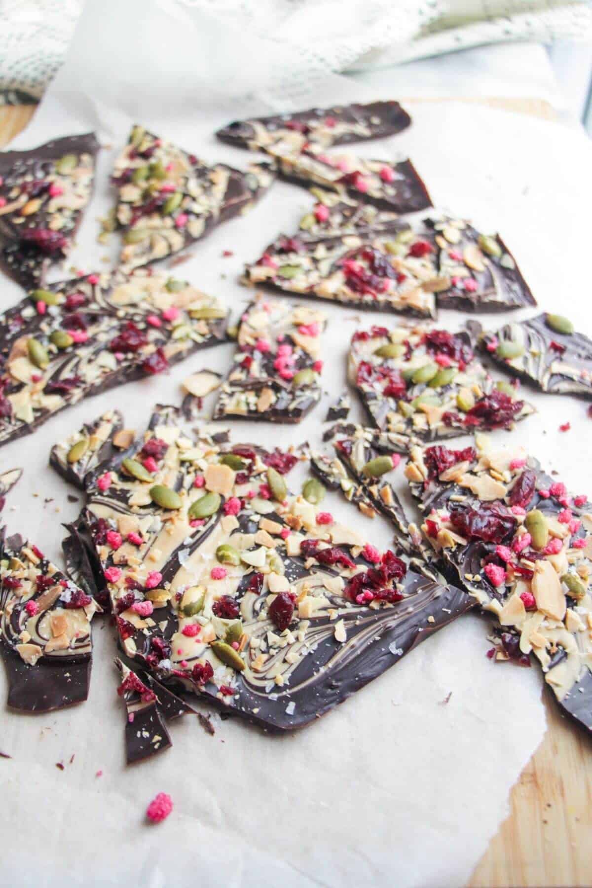 Chocolate almond bark broken into shards on a wooden board.