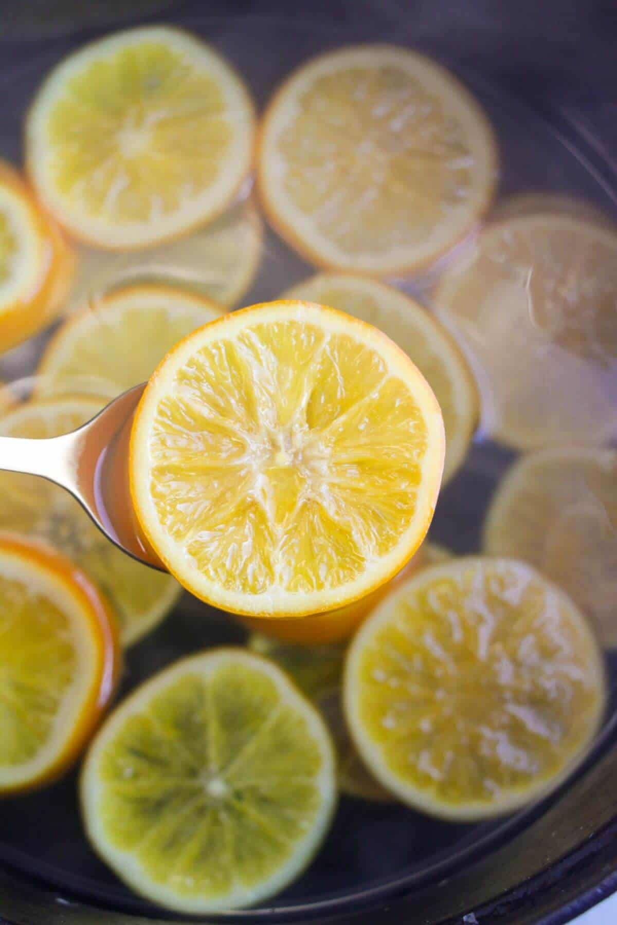 A simmered orange slice on a large gold spoon.