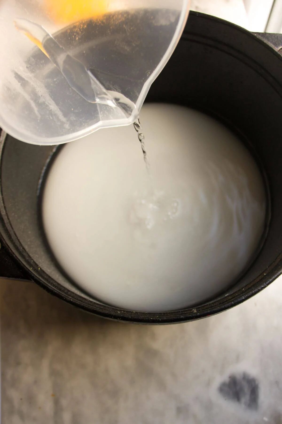Water being poured into a large pot with sugar in it.