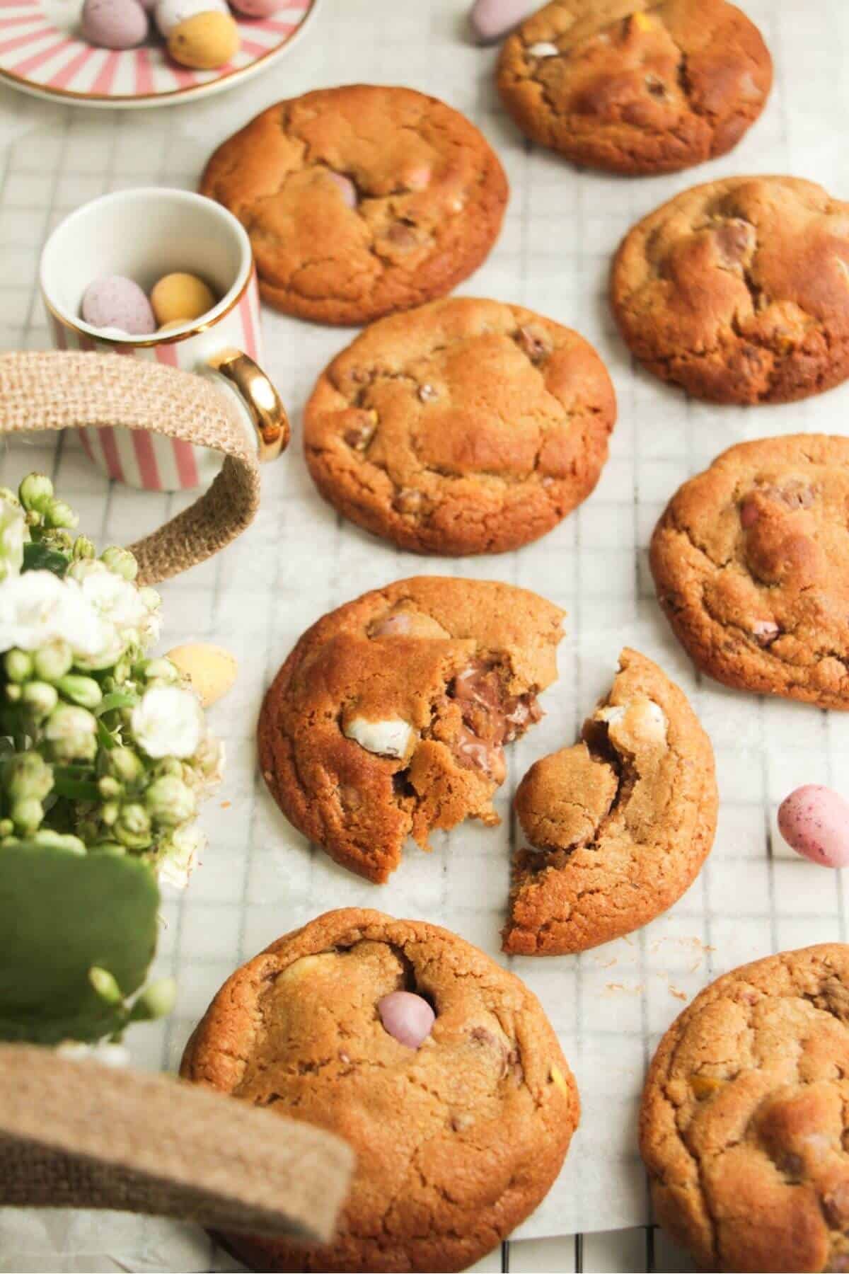 Mini egg cookies on baking paper, with more mini eggs on the side.