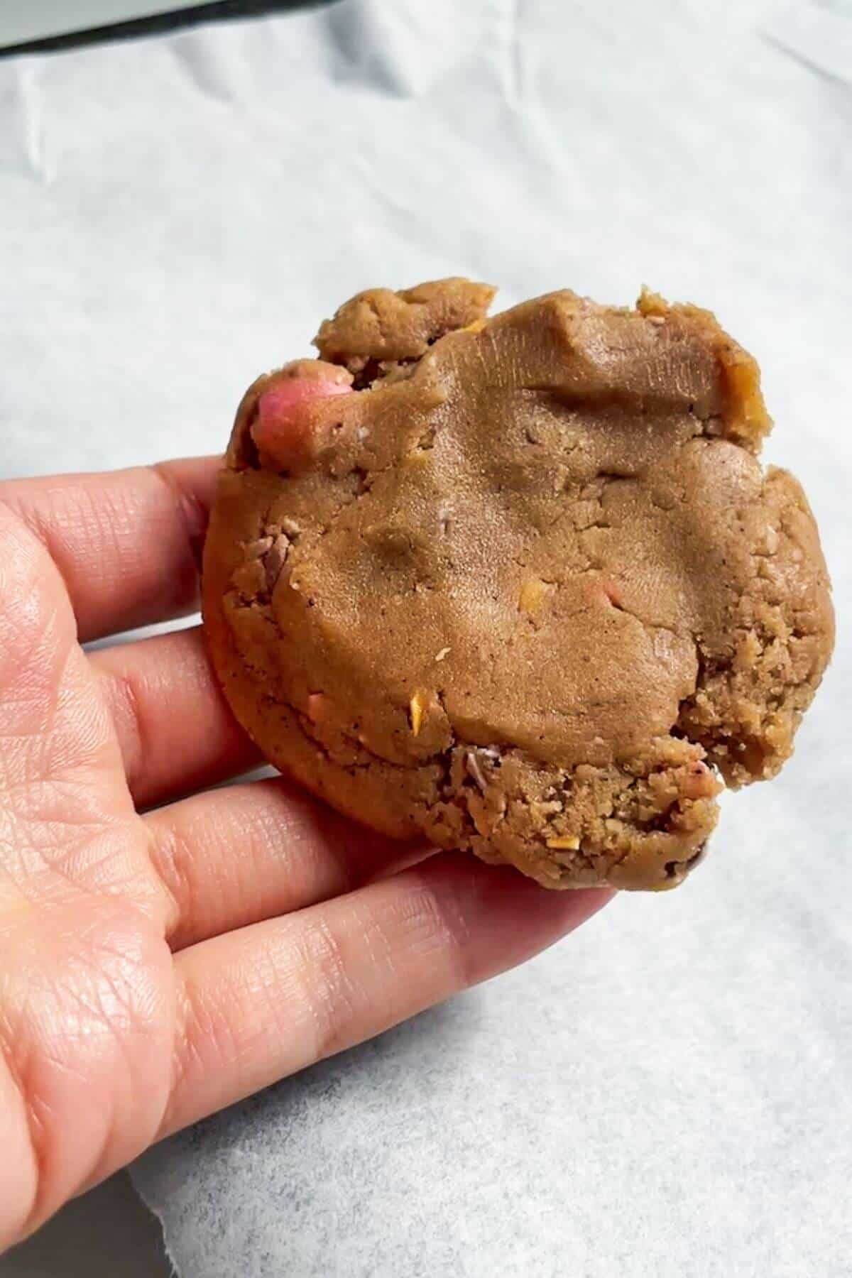 Hand holding a flattened piece of cookie dough.