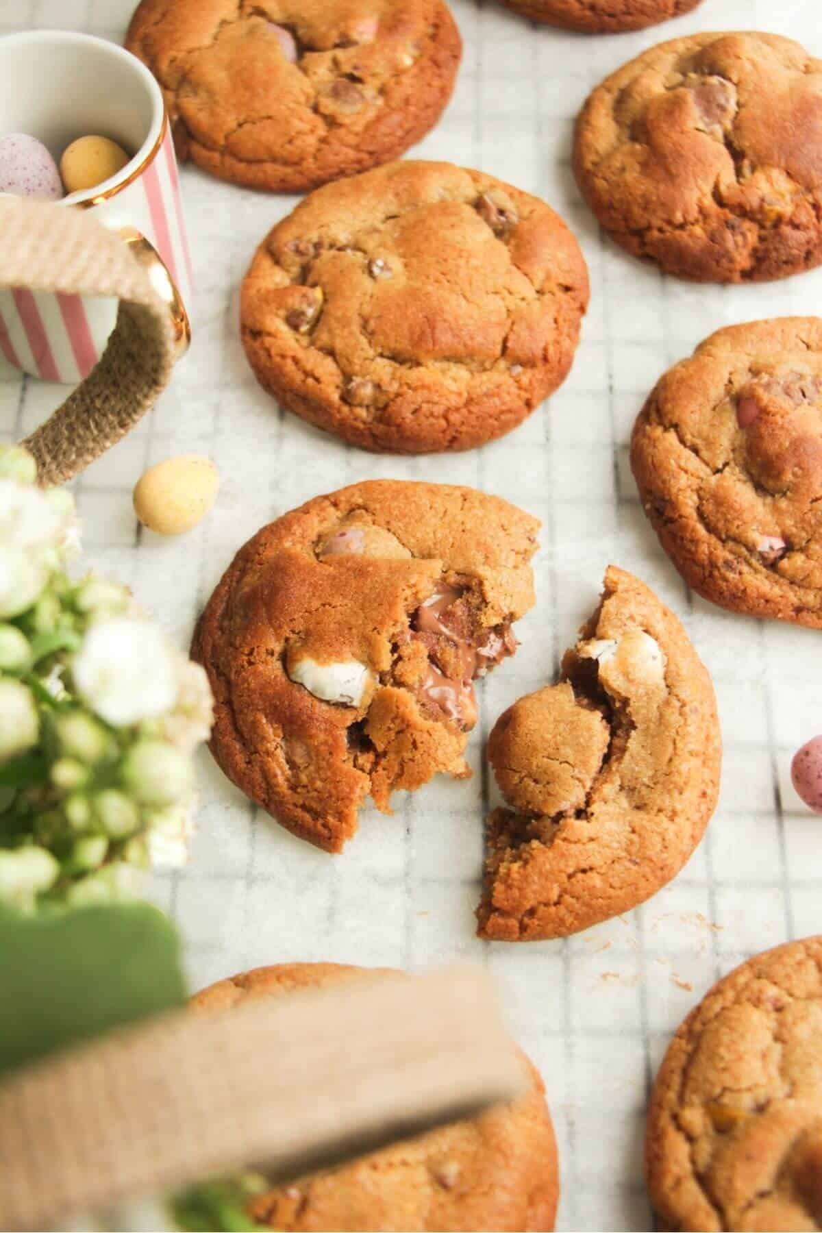 Mini egg cookies on baking paper, with more mini eggs on the side.