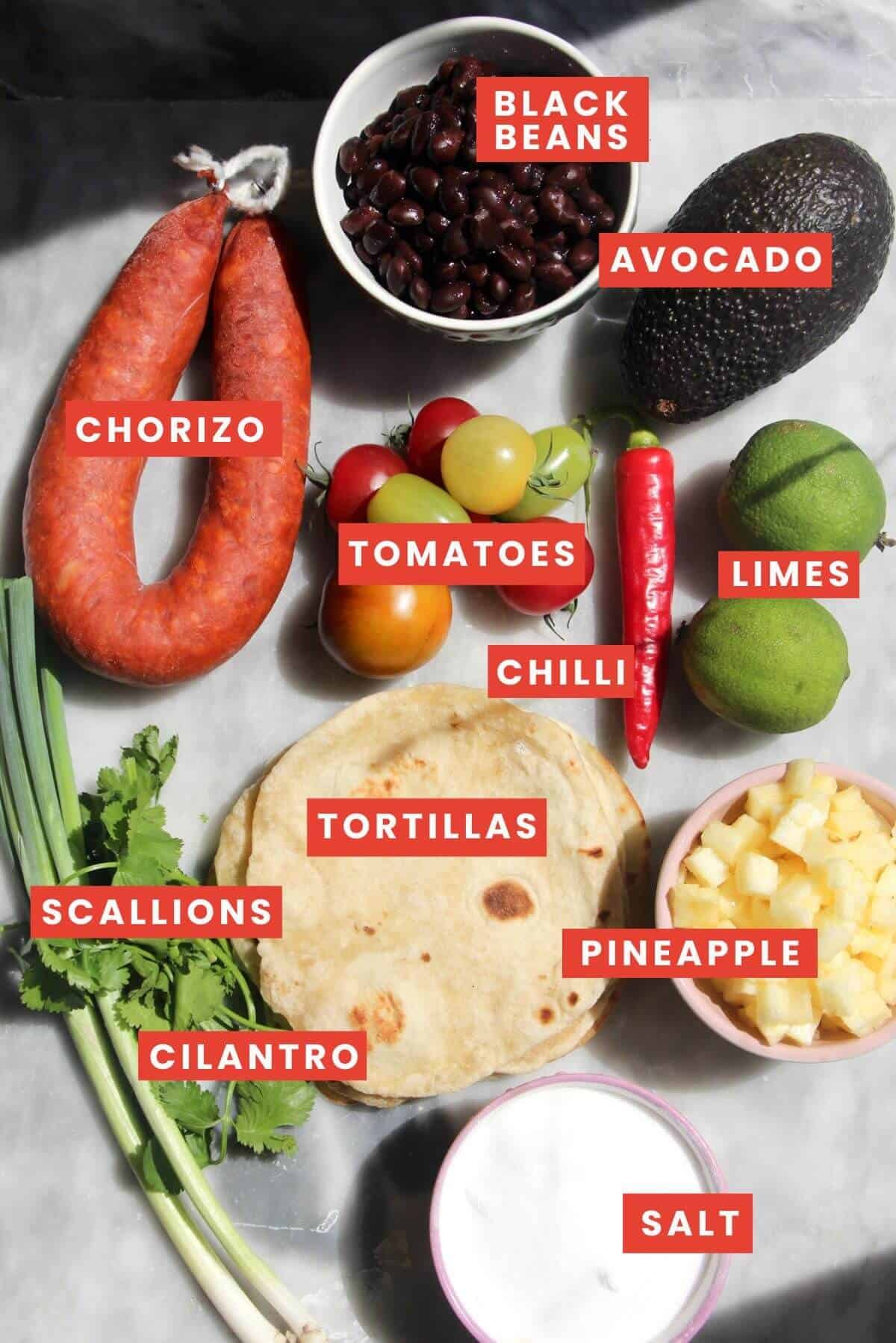 Ingredients for chorizo black bean tacos laid out on a grey marble background.