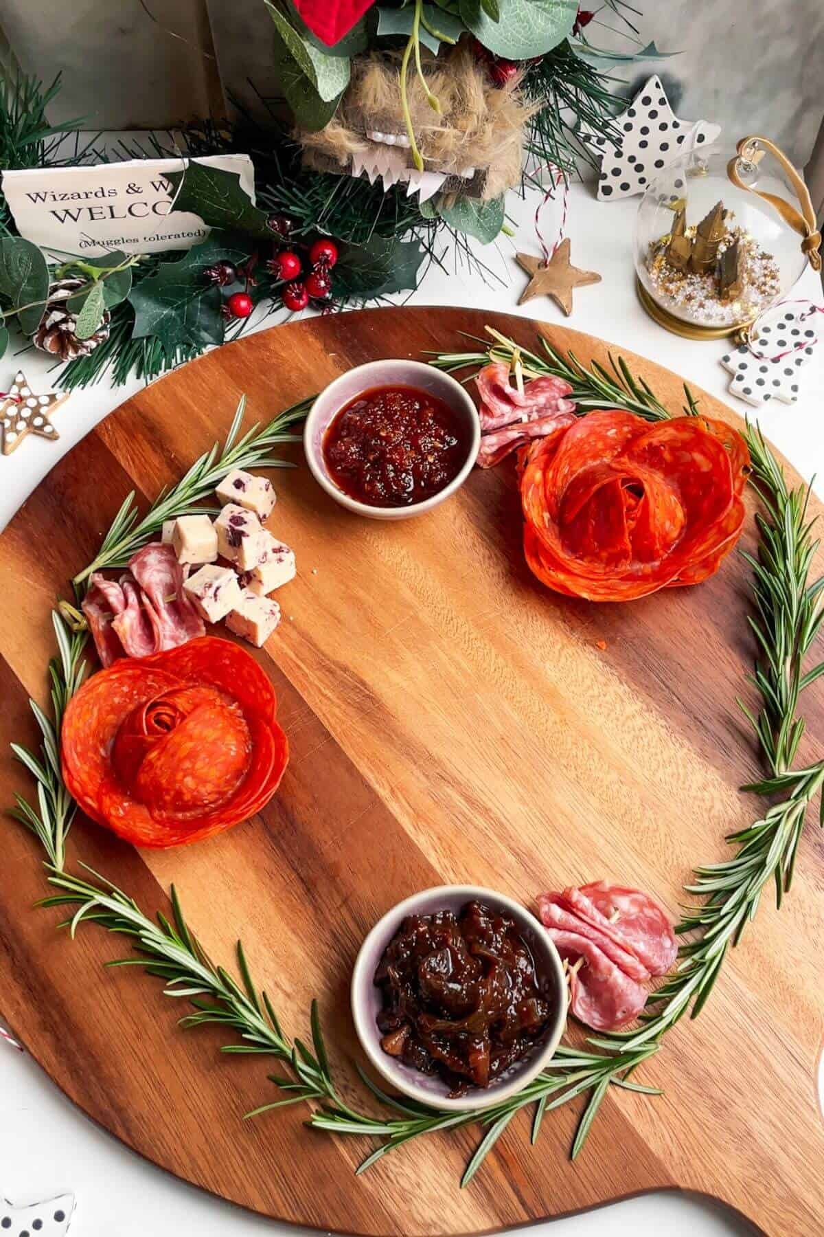 Meat, cheese, and bowls of relish on a wooden board.