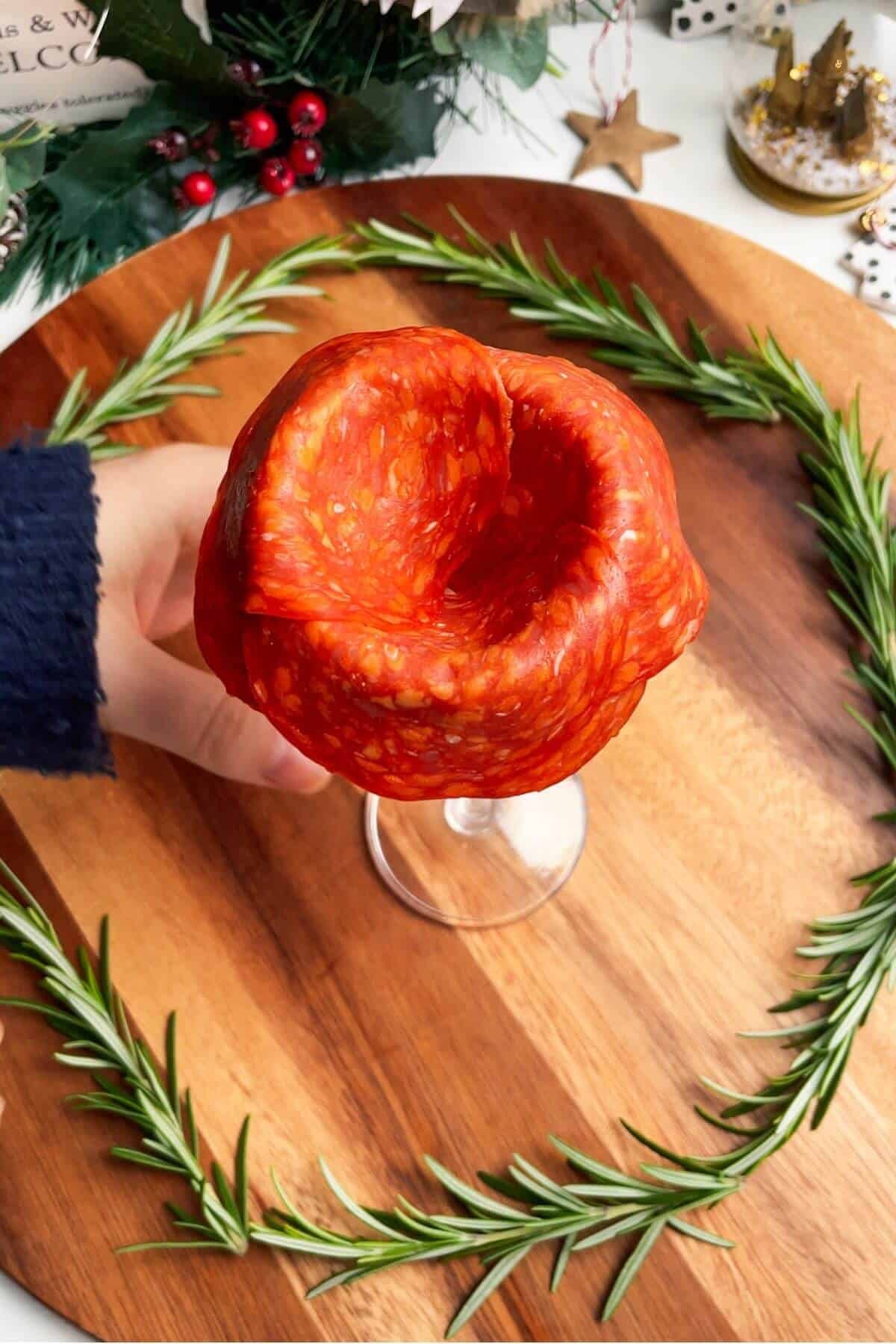 Salami layered around the edge of a wine glass.