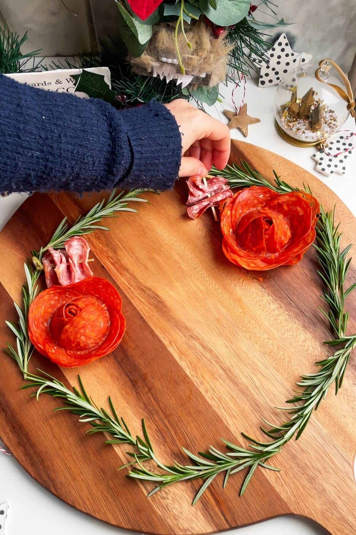 Placing skewered salami onto a large round wooden board.