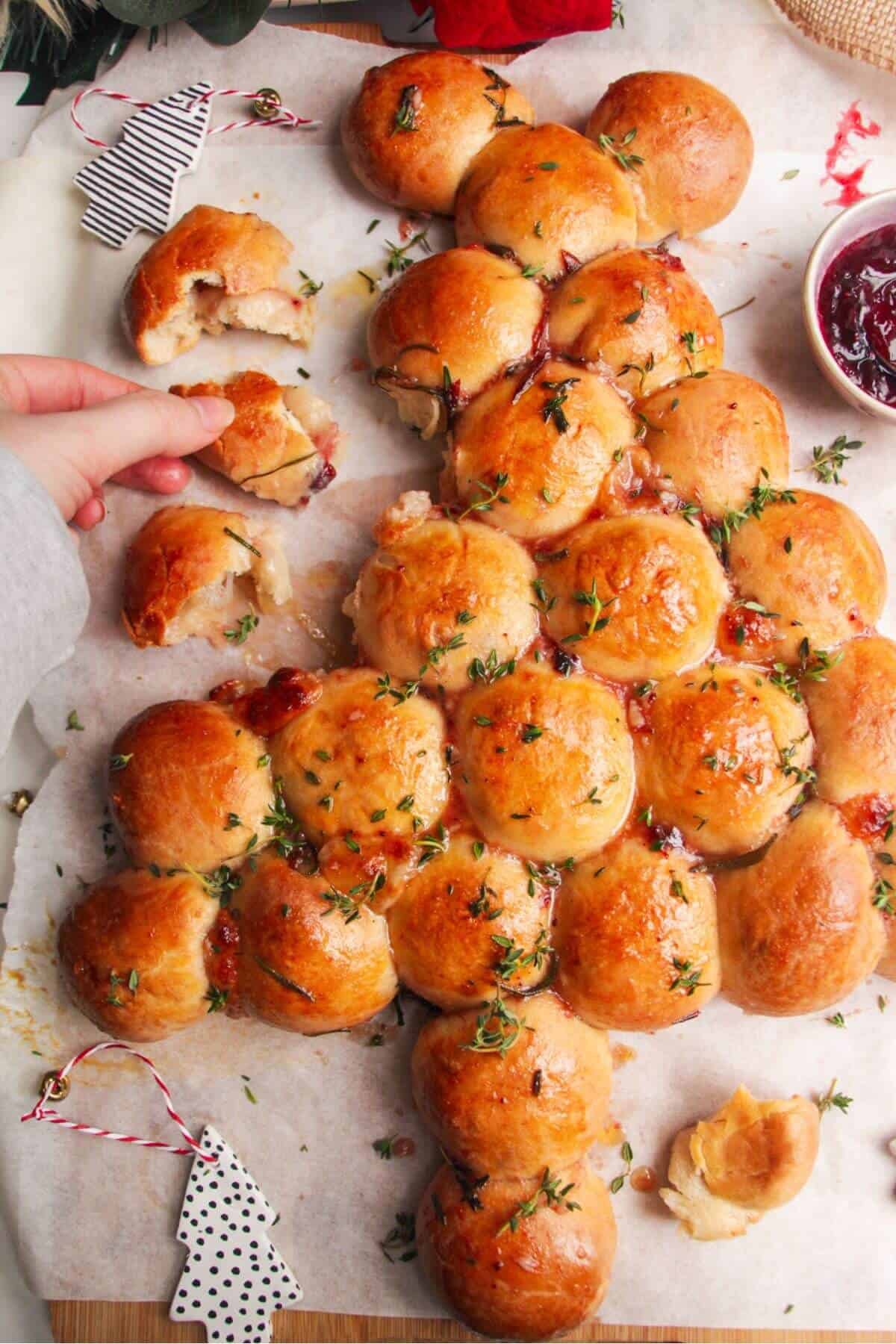 Hand pulling out a stuffed dough ball from Christmas tree shaped dough balls.
