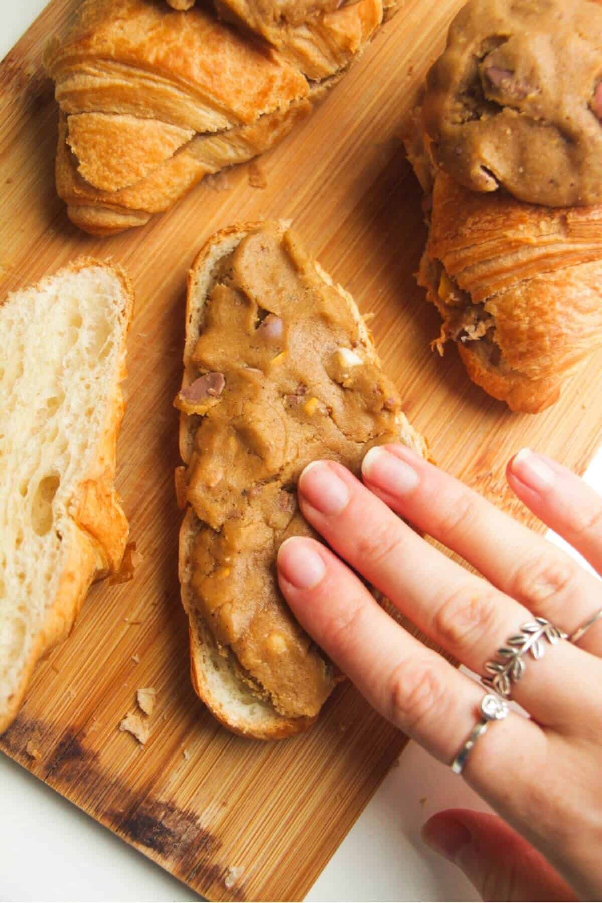 Hand pressing cookie dough into a sliced croissant.