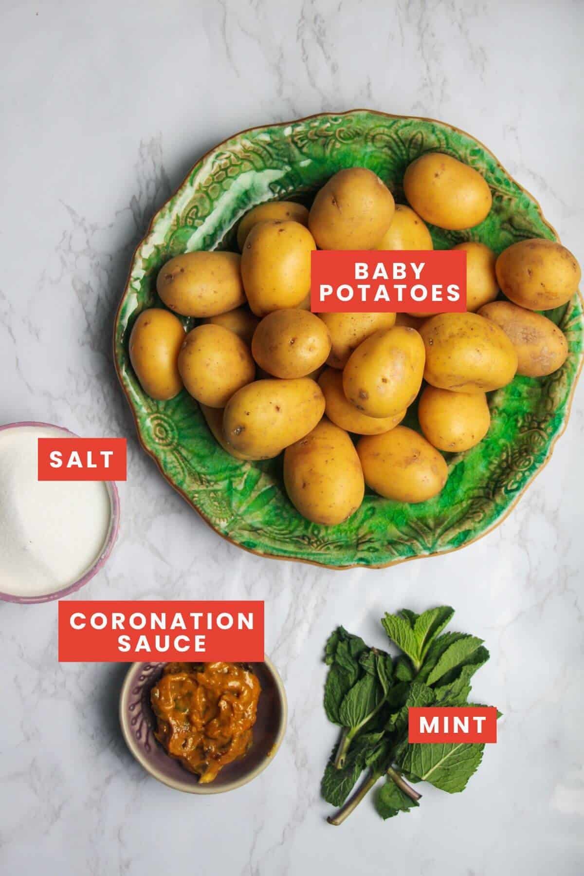 Ingredients for coronation potato salad on a white marble background and labelled.