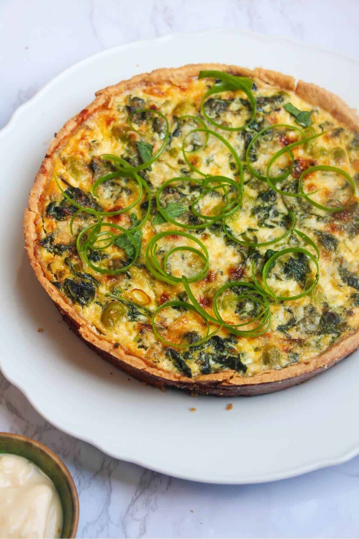 Coronation quiche on a scalloped white plate.