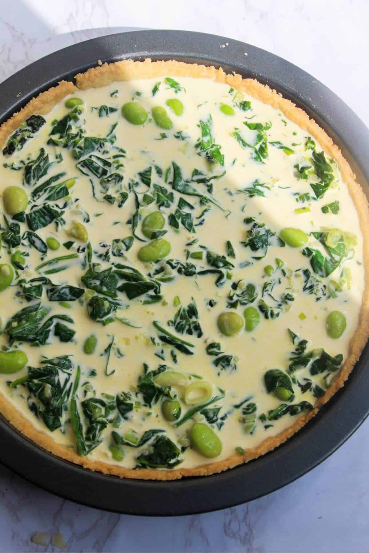 Custard in pastry case with spinach, edamame and mint leaves.