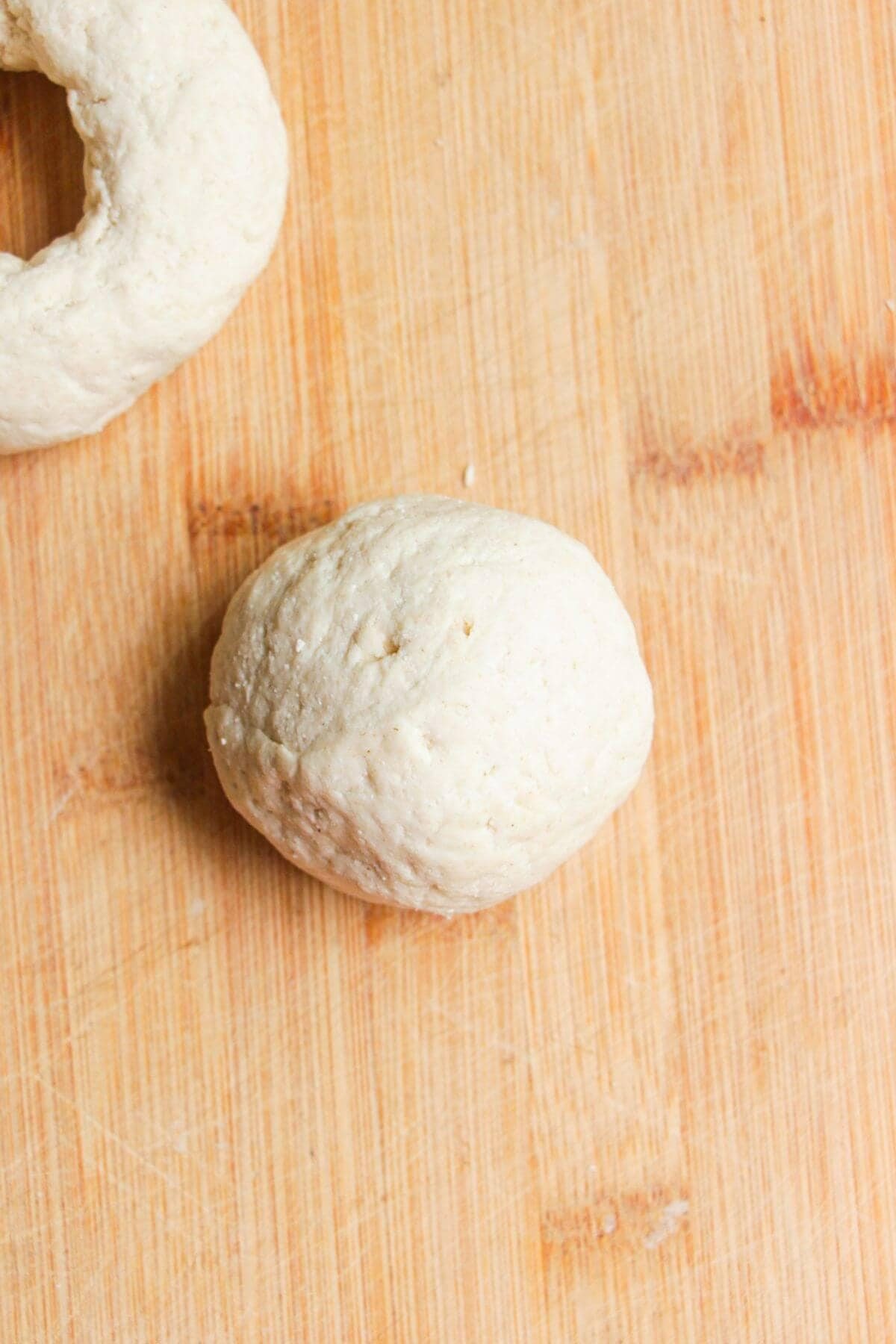 Bagel dough formed into a ball on wooden board.