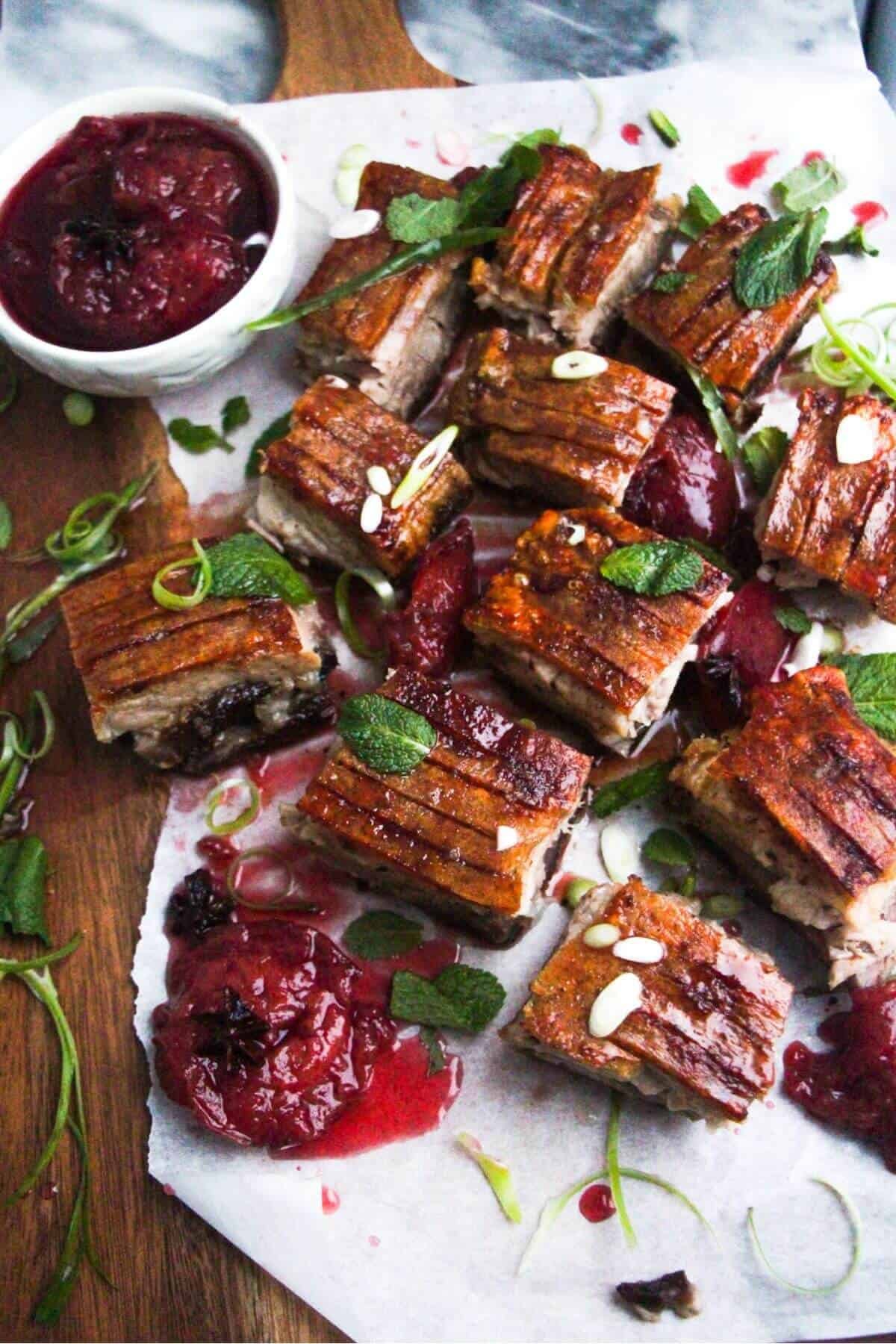 Square pieces of slow roasted pork belly on a wooden serving platter.